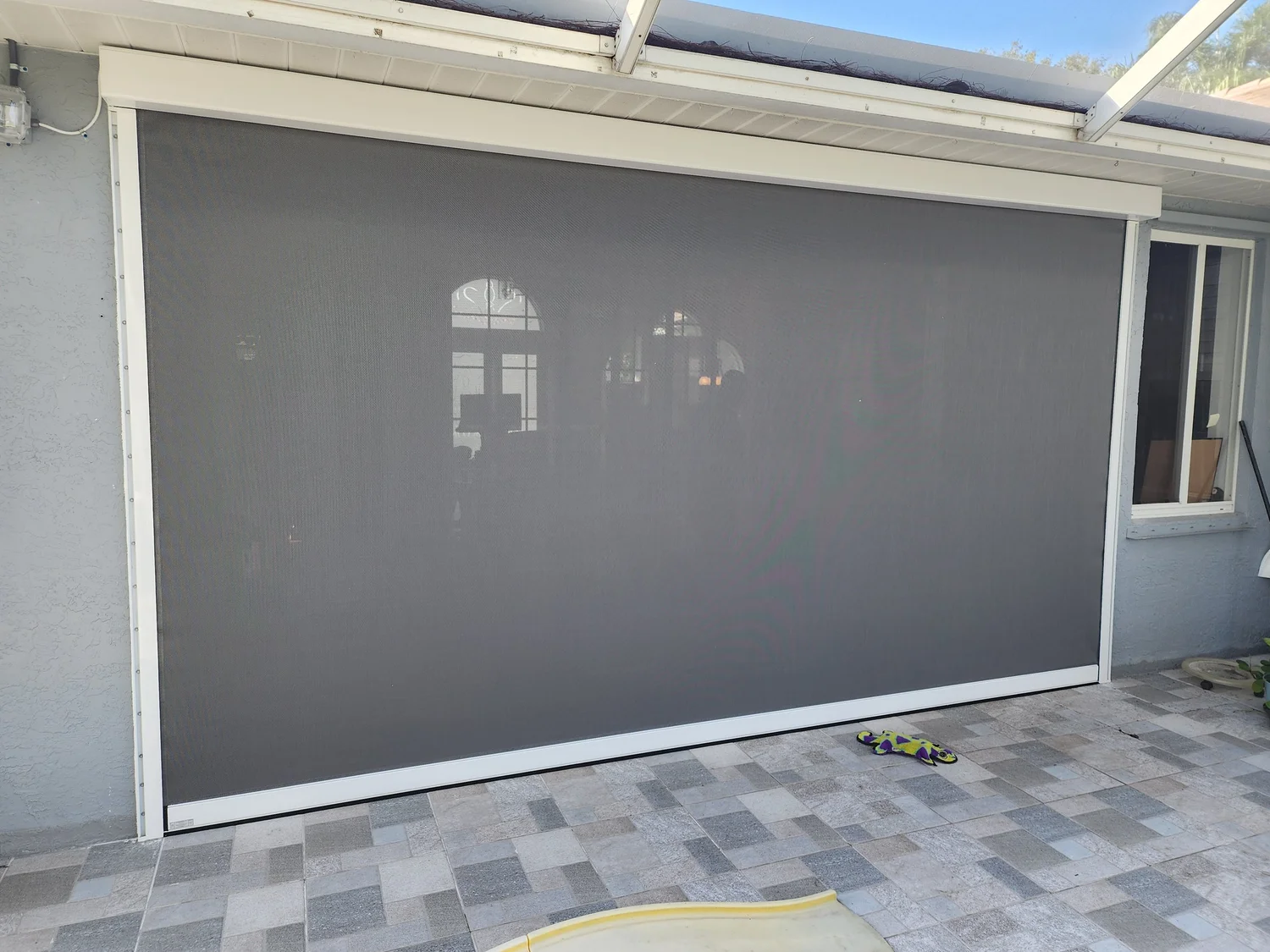 Retractable UltraShield screen covering a patio opening, installed by Expert Shutter Services, serving Palm City, FL