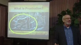 Dr. Tom Wadsworth standing in front of screen with an image of a person prostrating in worship