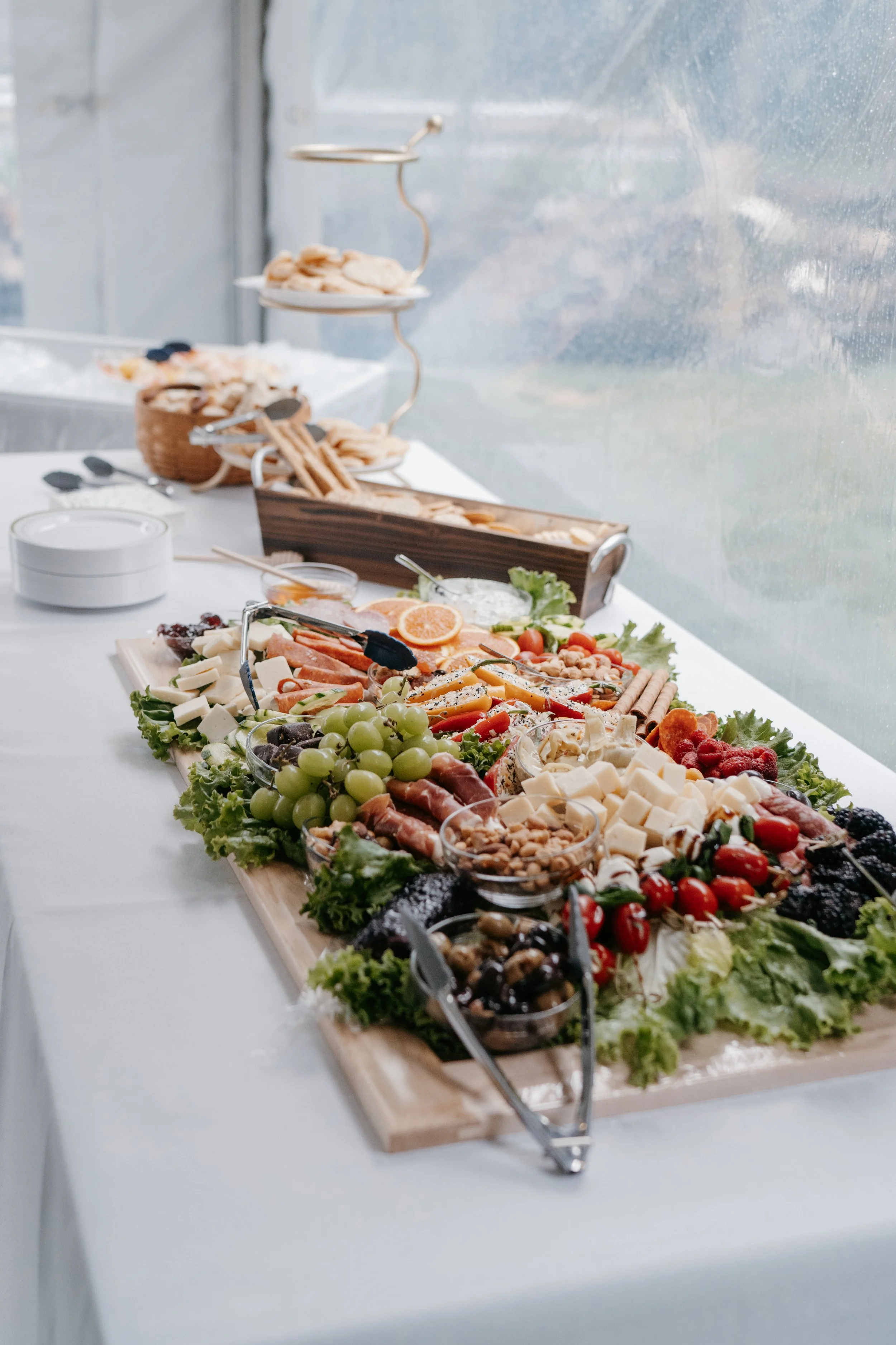 Luxury grazing table with charcuterie, fresh vegetables, gold flatware, and illuminated 2026 sign at an elegant New Year’s Eve celebration.
