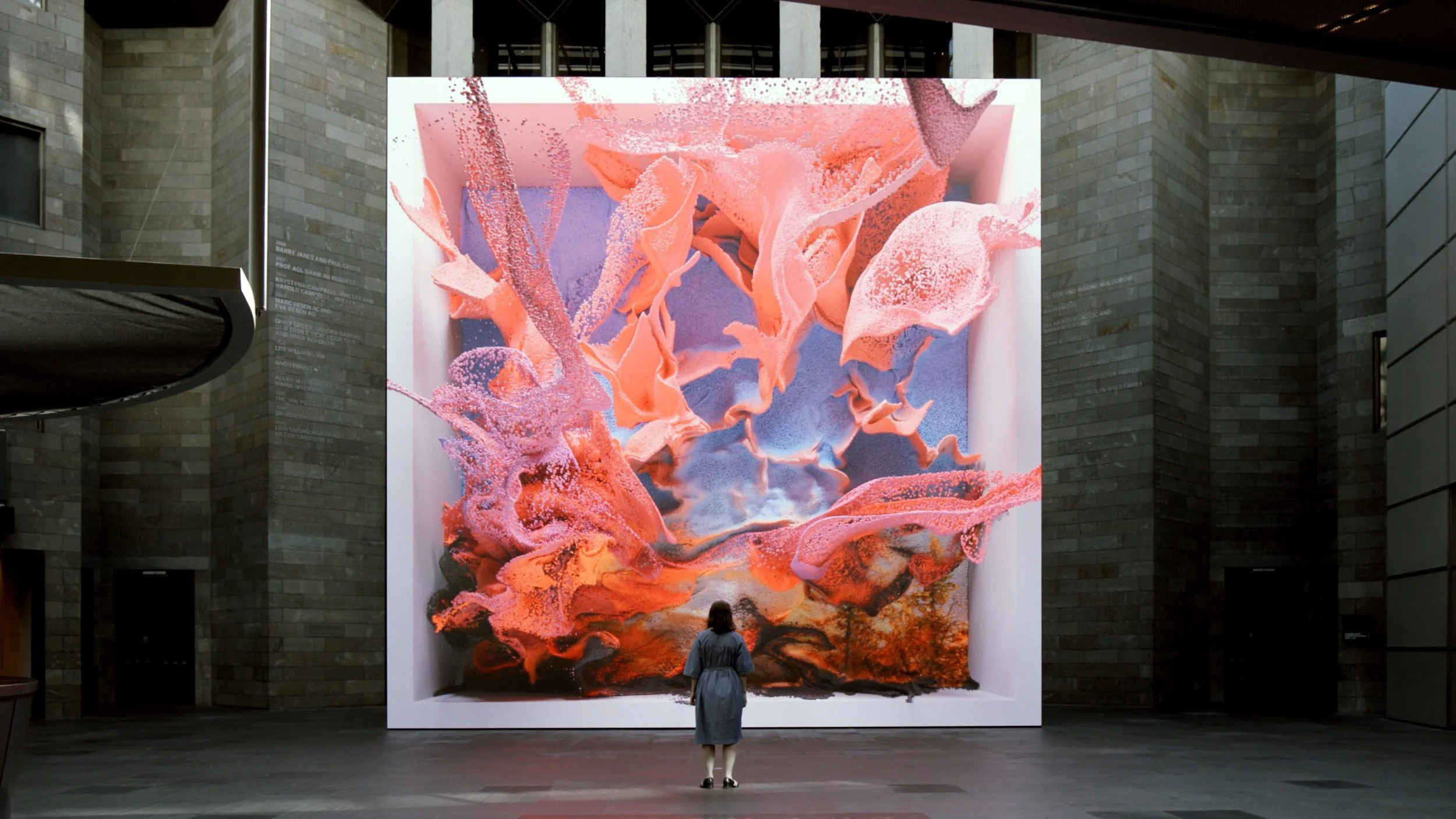 A person stands in front of a digital art display
