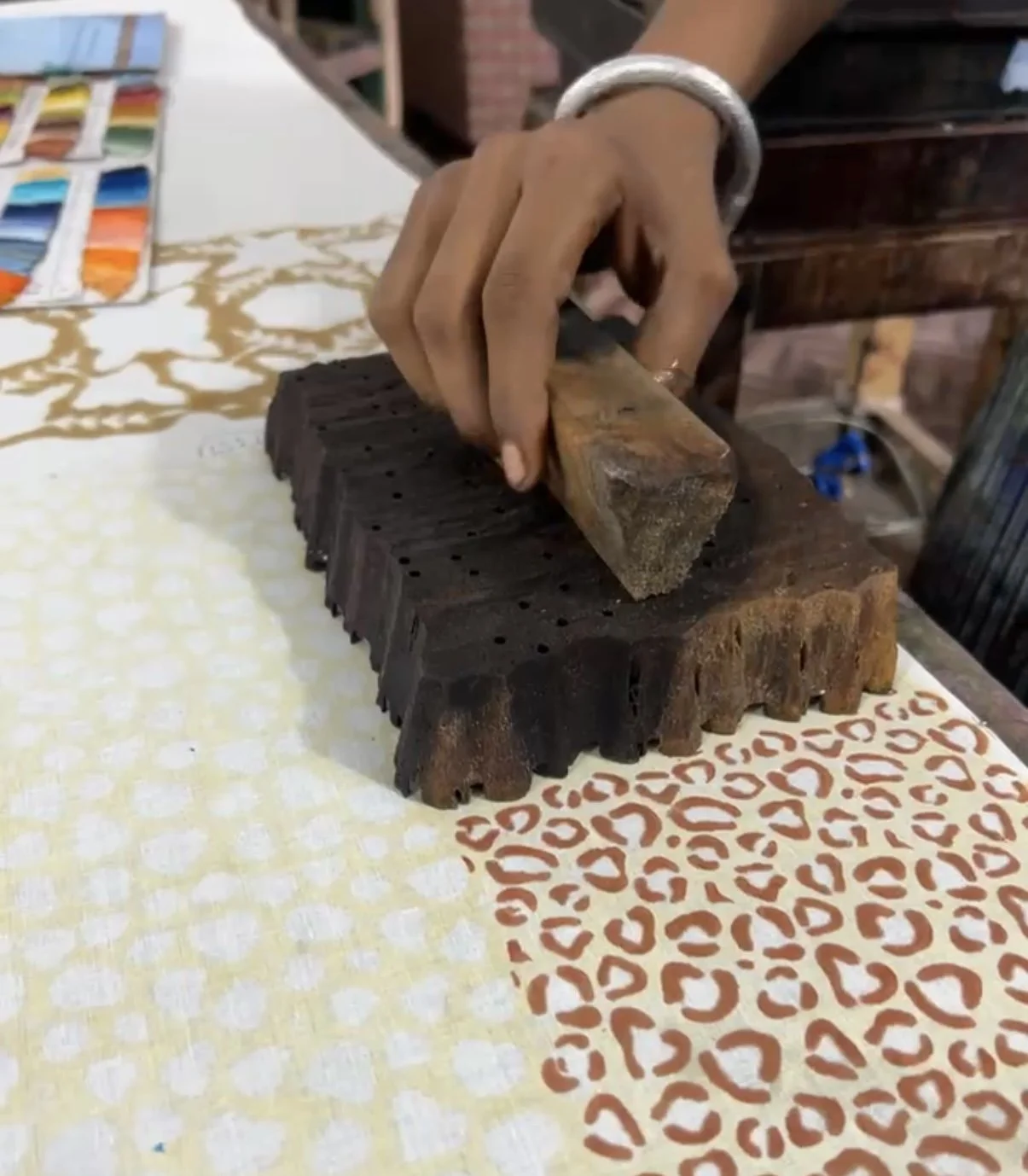 Main tenant une pièce de bois sur un étau, dans un environnement de travail ou d'artisanat.