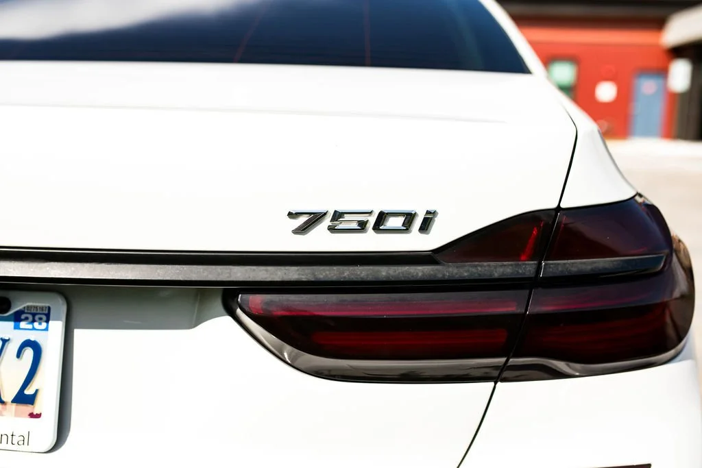 Close-up of the rear of a white car, showing the model badge '750i' and part of the taillight.
