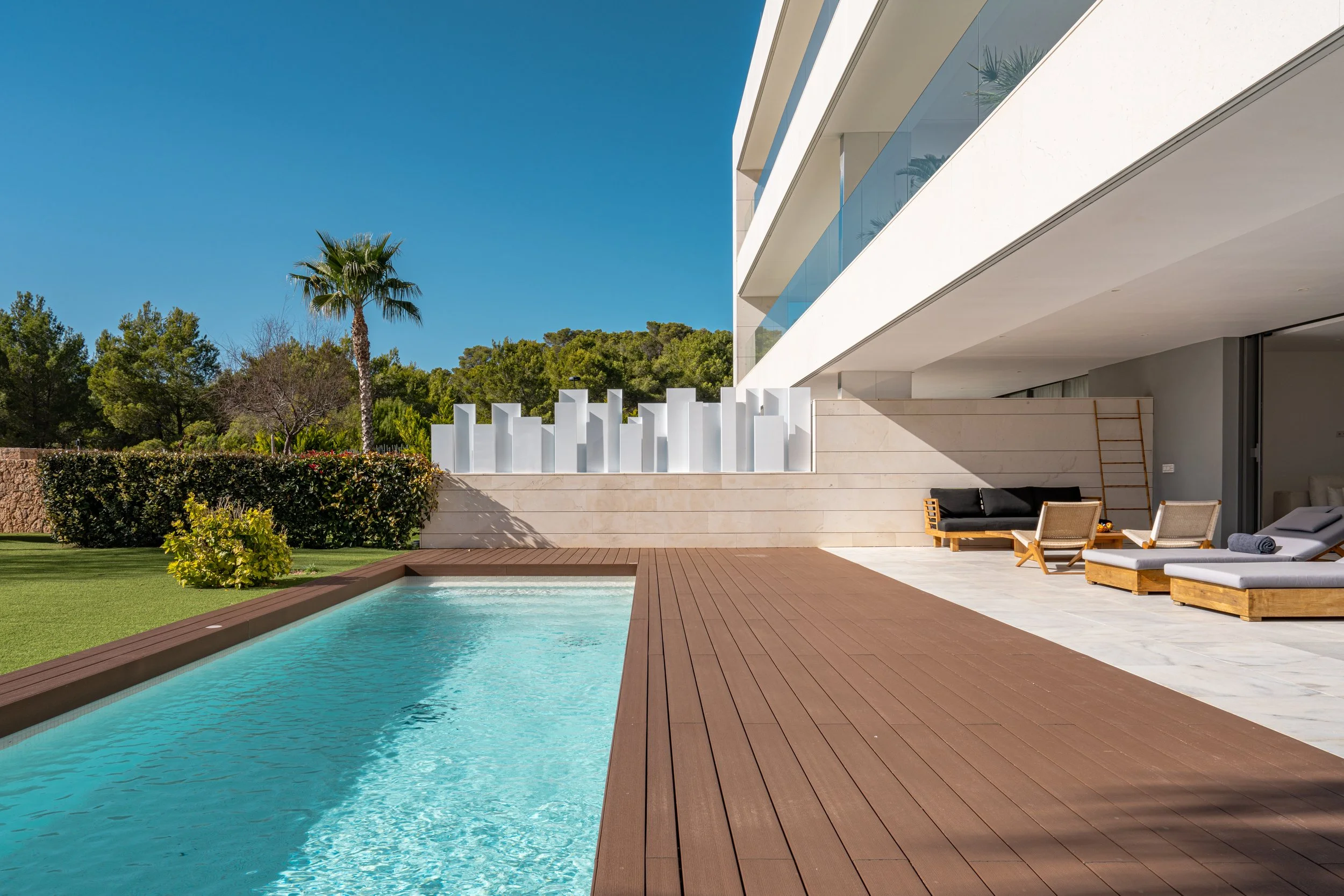 Modern house with a swimming pool in the backyard, surrounded by greenery and lounge chairs.