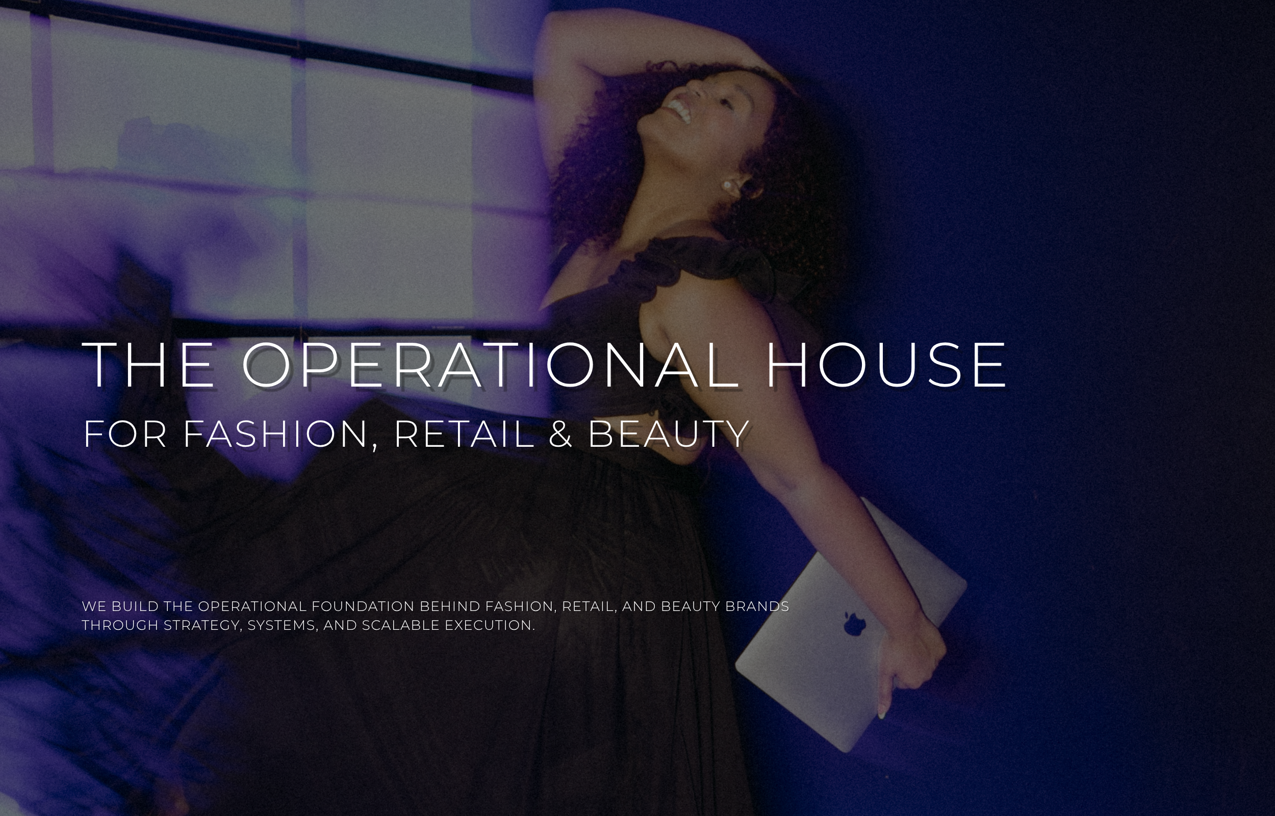 Founder of MEESH Agency, the Operational House for Fashion, Retail & Beauty, holding a laptop in an editorial studio representing operational strategy, project management, and business systems for creative brands.