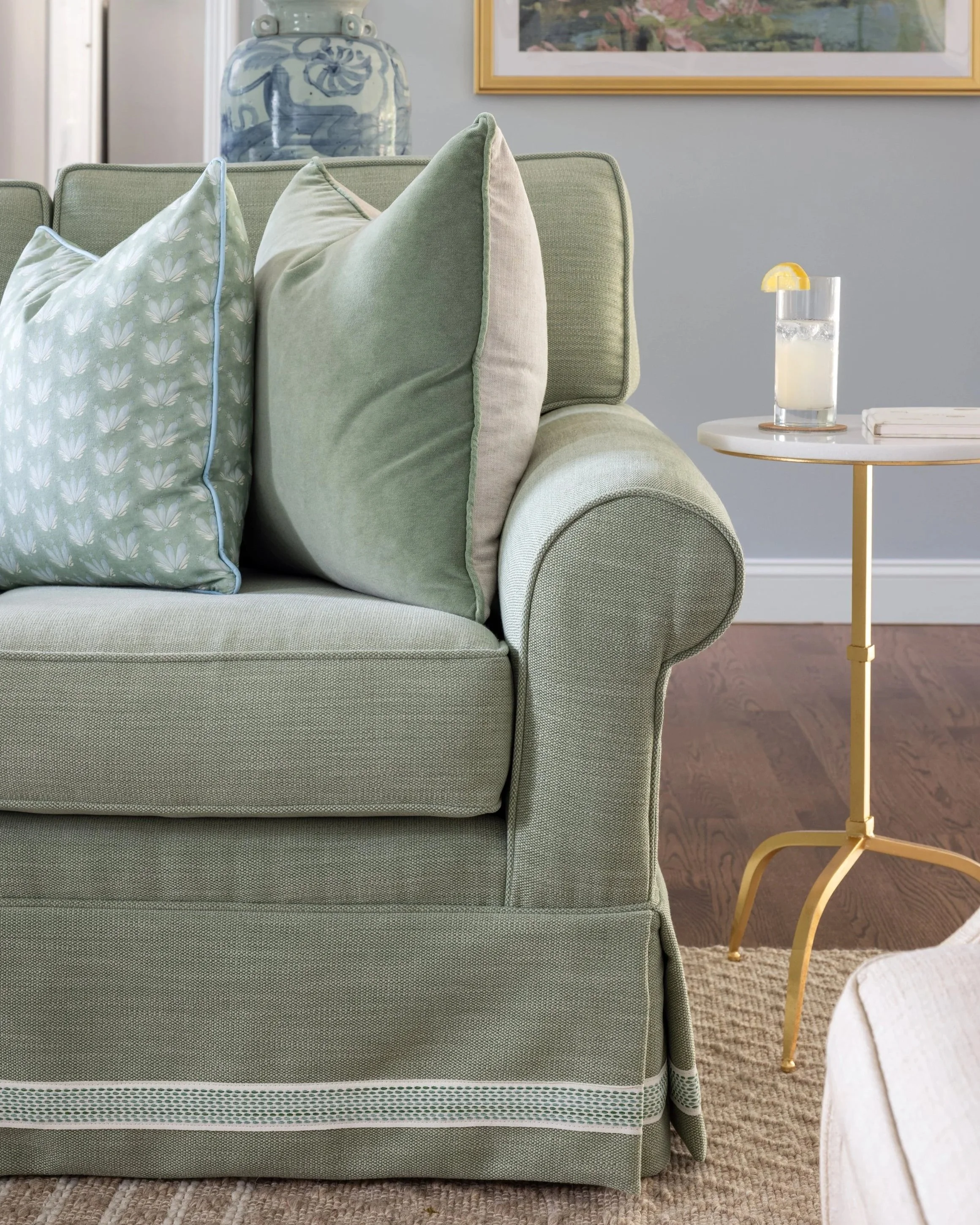 Reupholstered antique curved-arm sofa with sea foam slip cover with pleated skirt, custom trip and refreshed cushions