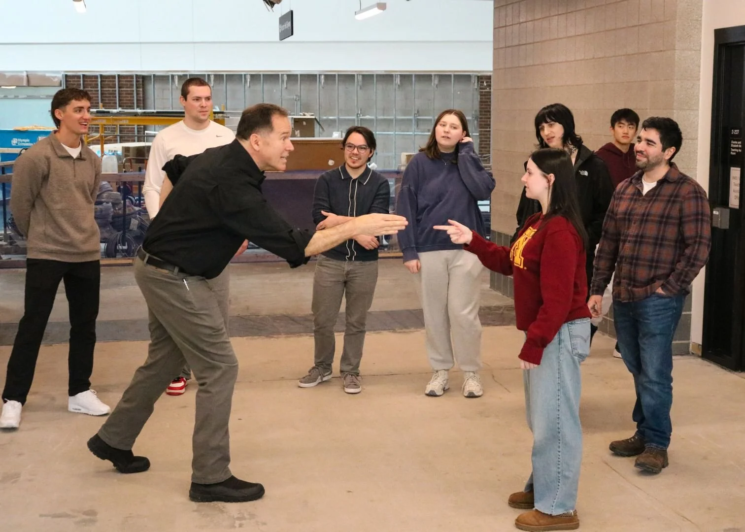 A white male instructor pointing to a young white female during a workshop.