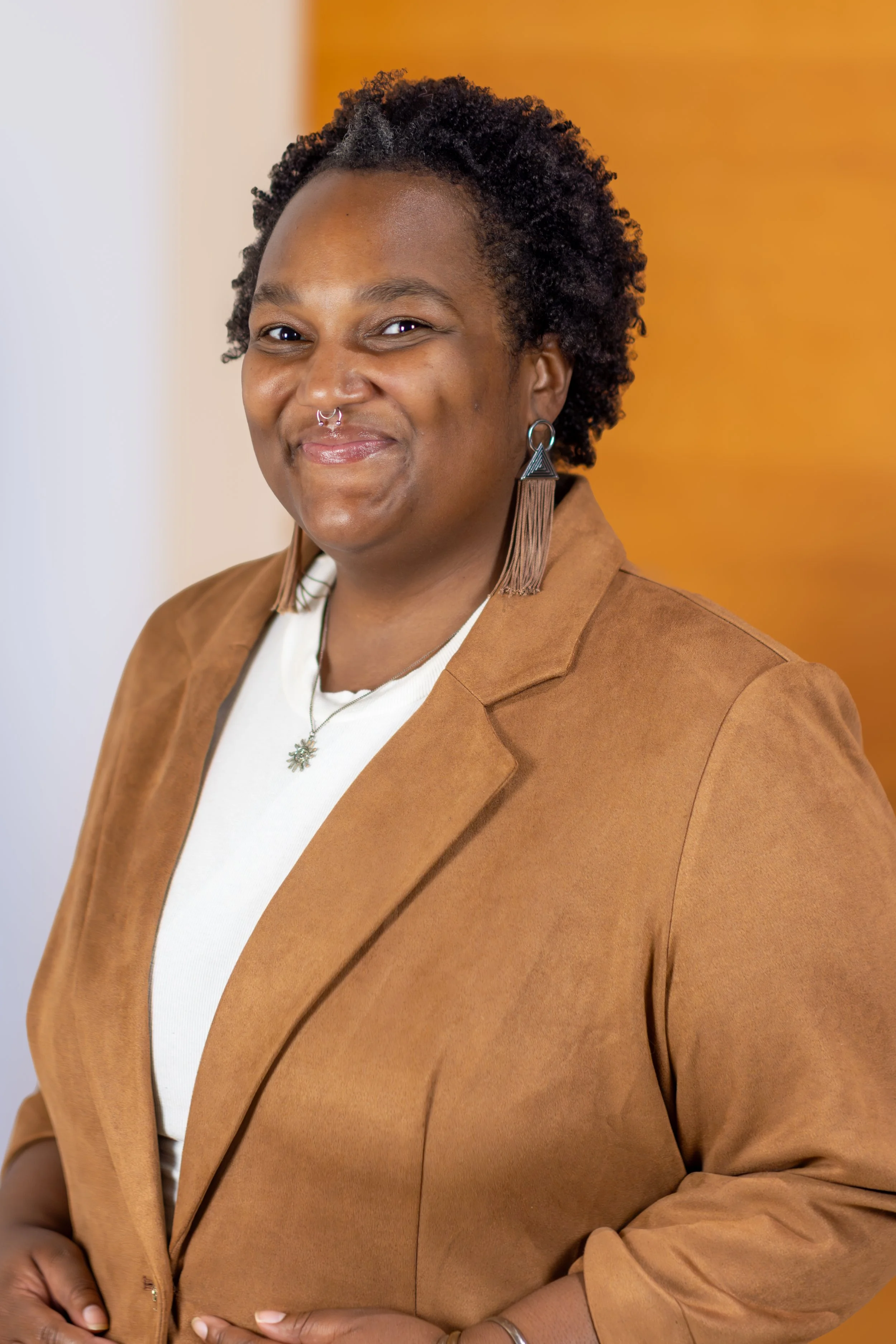 Actor Jada Pulley in a brown jacket in front of a yellow and white wall