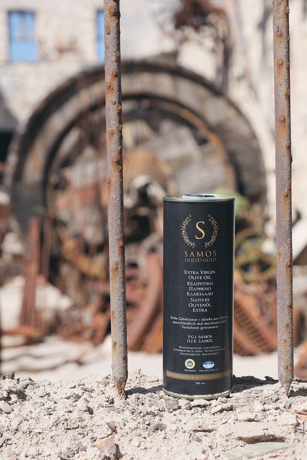 Burk med extra jungfruolivolja från Samos på ett öde industriområde, rostiga metallstänger i bakgrunden.