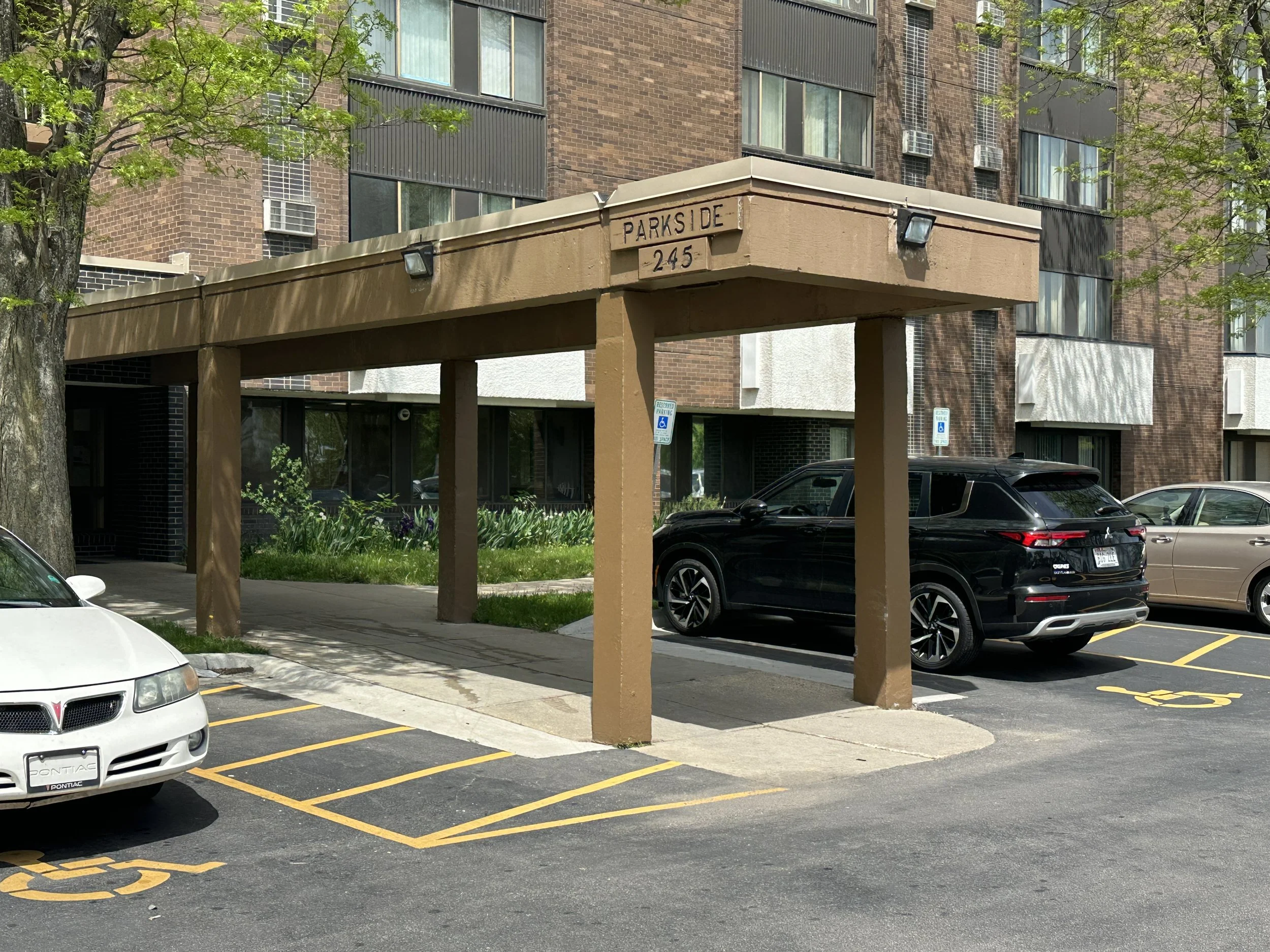 Covered parking lot entrance to a brick apartment building with a sign that reads, Parkside.