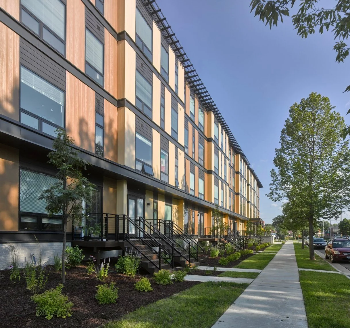 Tree lined street with landscaped entries to apartment homes at Ella Apartments.