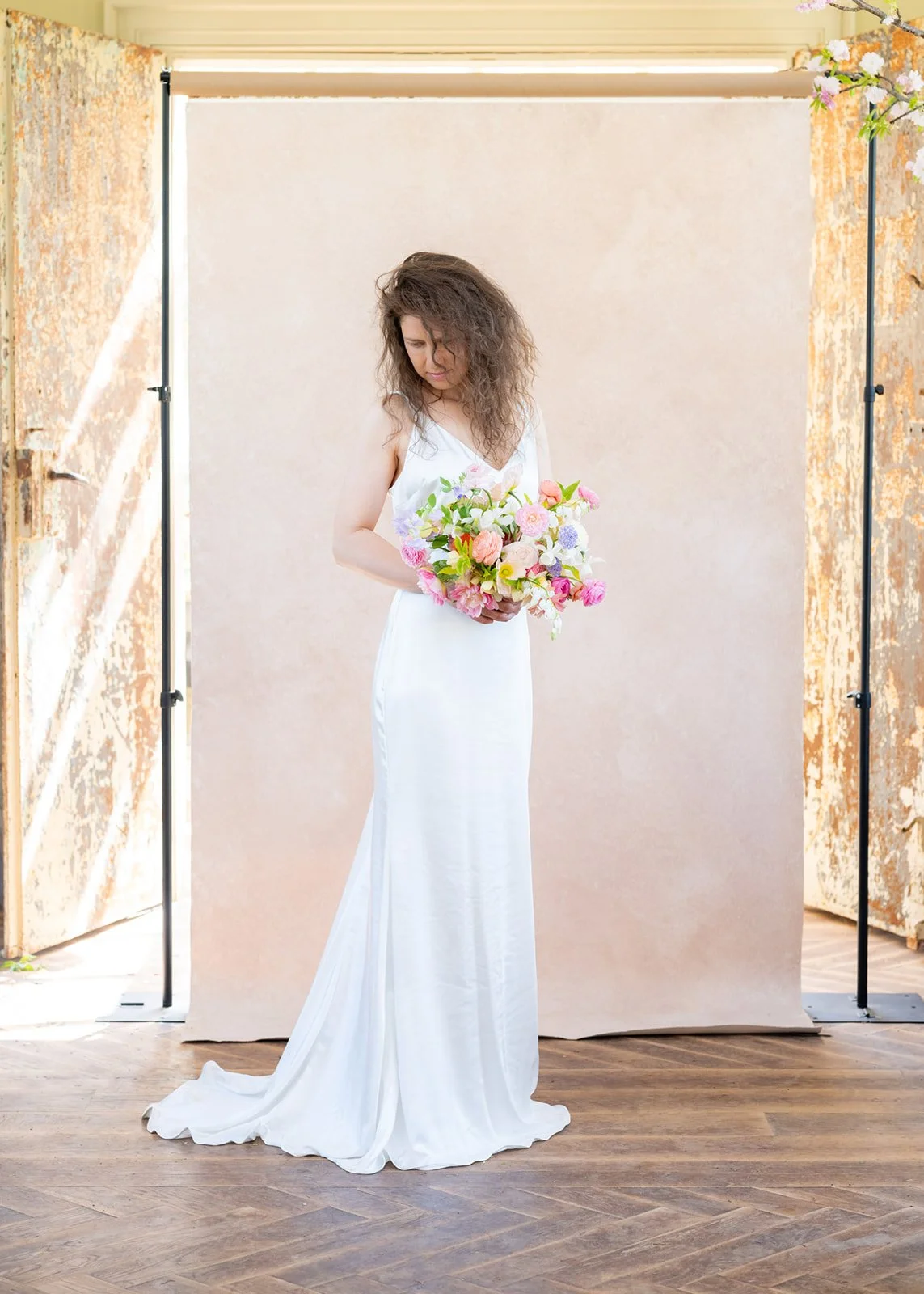 full-length bridal portrait of bride holding bouquet photographed in front of a hand-painted photography backdrop