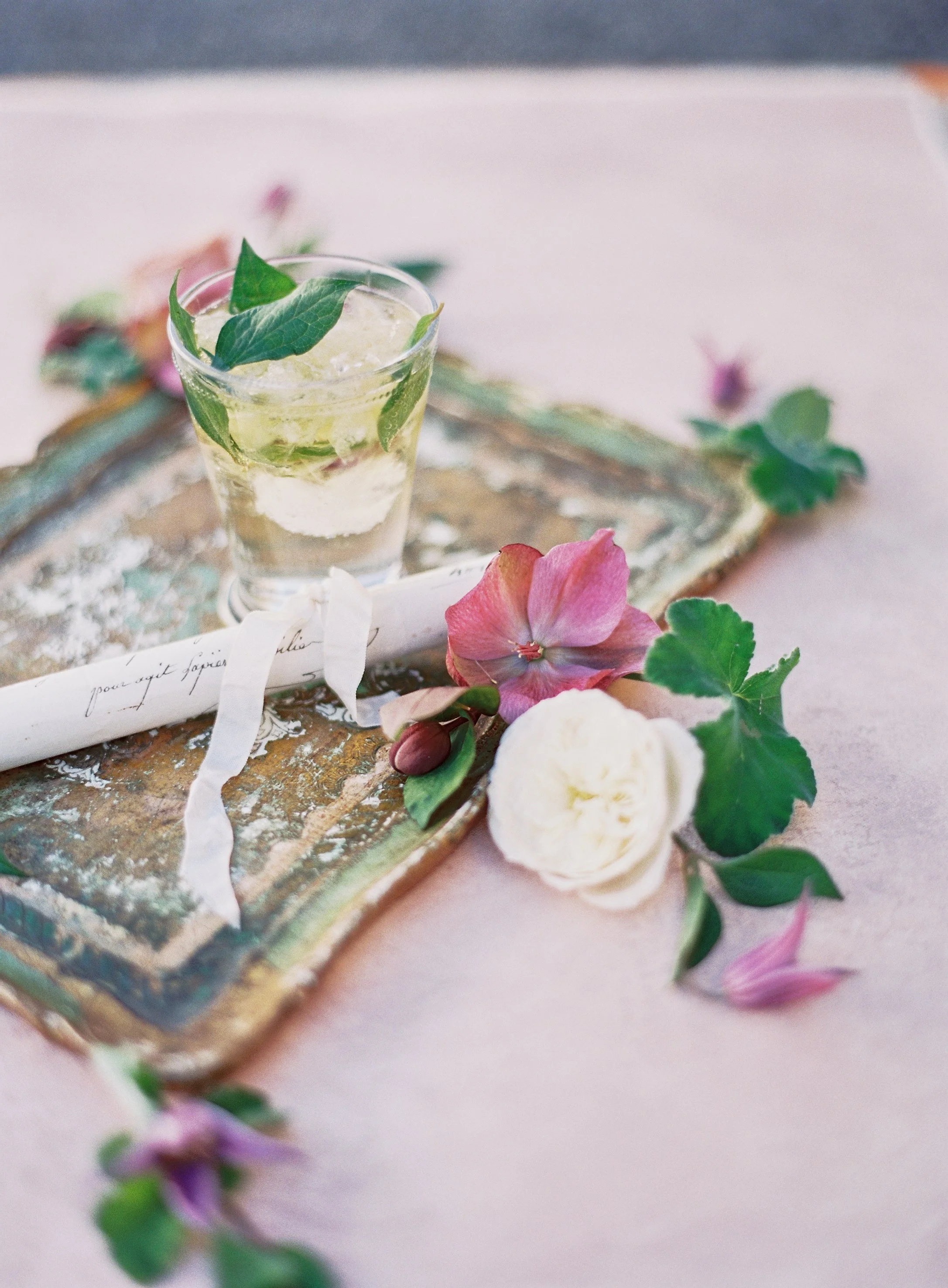 wedding cocktail with botanical garnish on vintage tray with floral details
