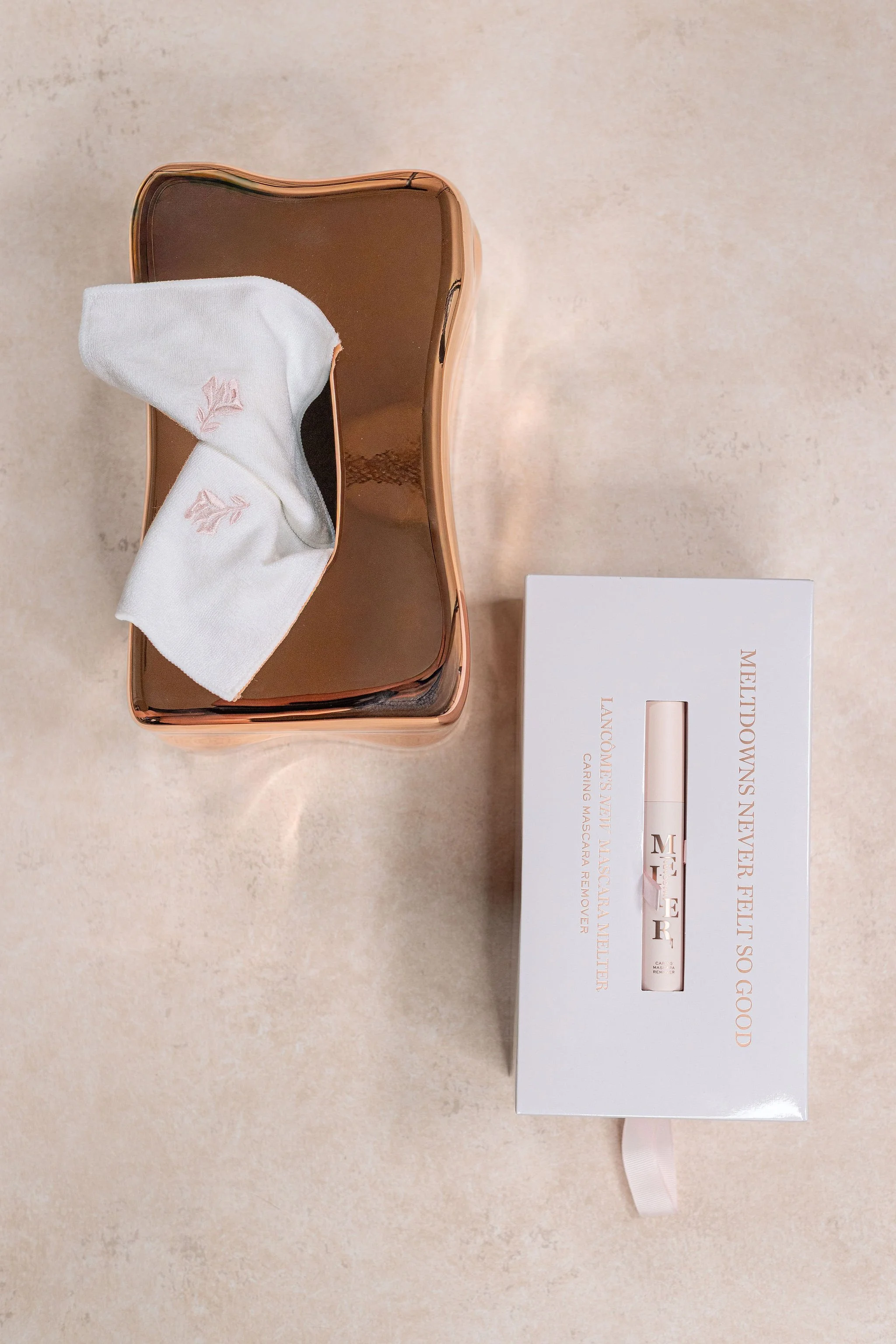 luxury bridal cosmetics flat-lay on a warm-neutral hand-painted styling surface