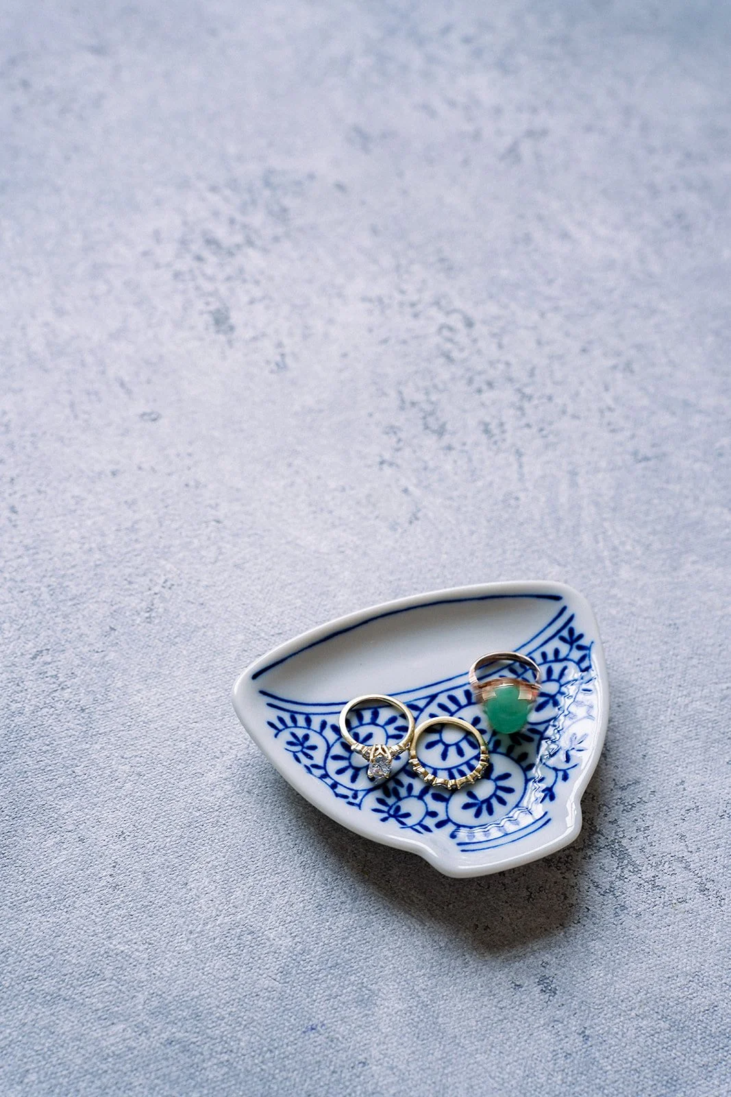 gold rings and emerald gemstone ring in a ceramic dish on a Chasing Stone Celestite flat lay surface