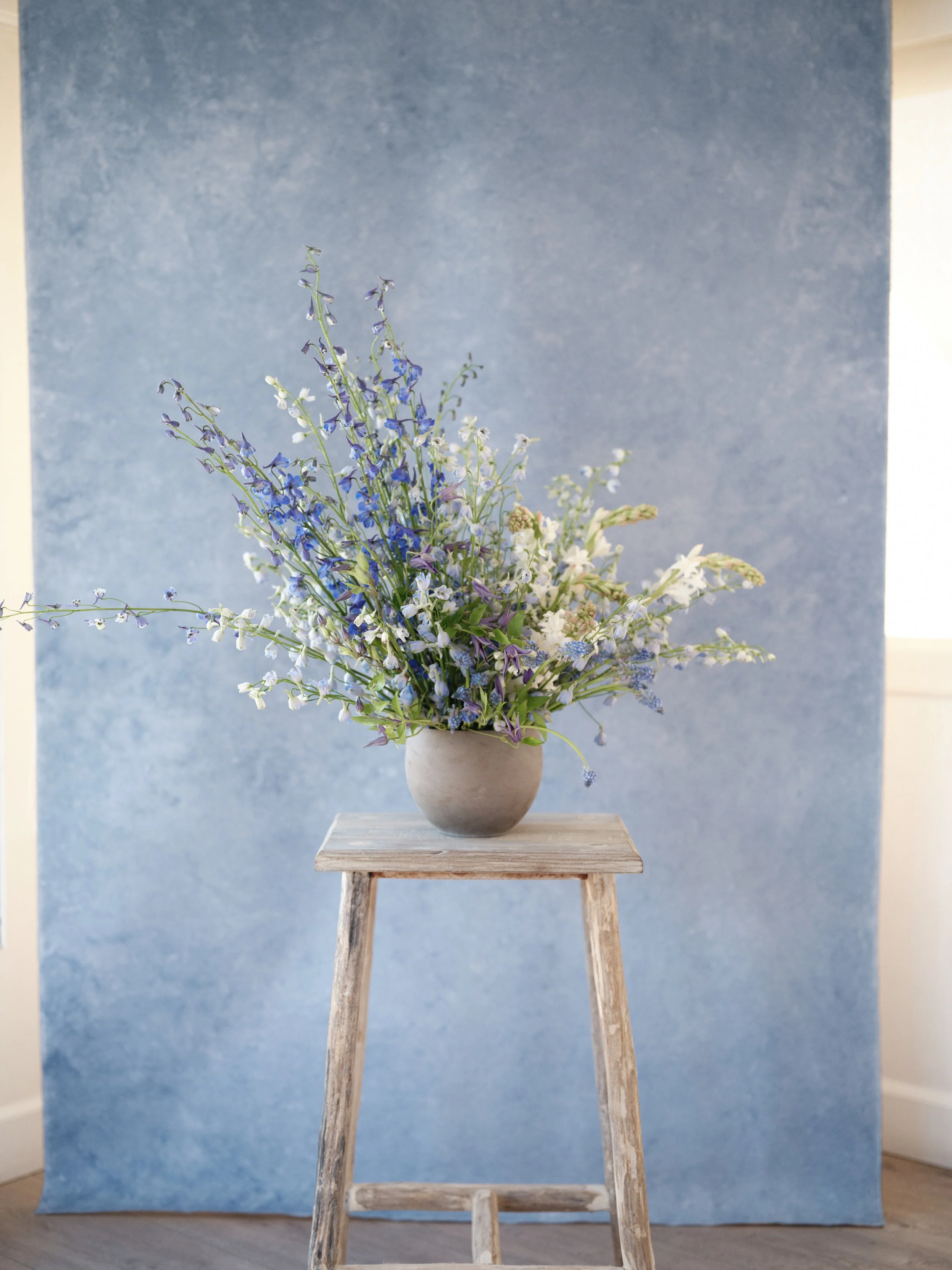 lapis hand-painted dusty blue canvas backdrop with wedding floral arrangement styling on rustic table
