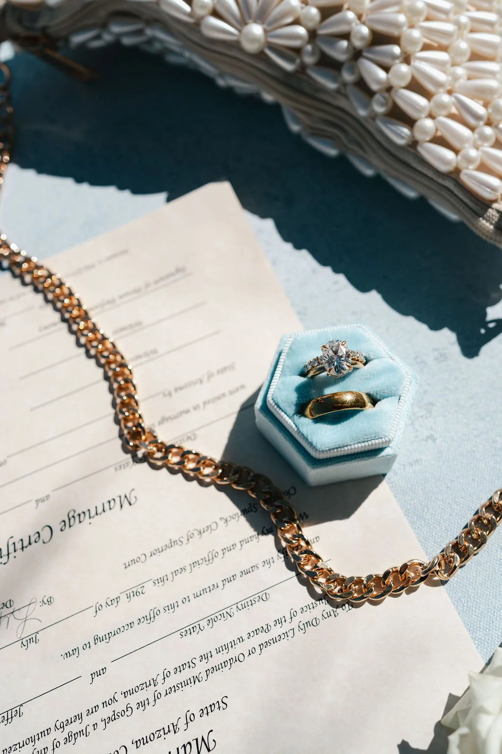 bridal jewelry flat lay with diamond ring and gold wedding band in a velvet ring box on a Chasing Stone hand-painted canvas surface