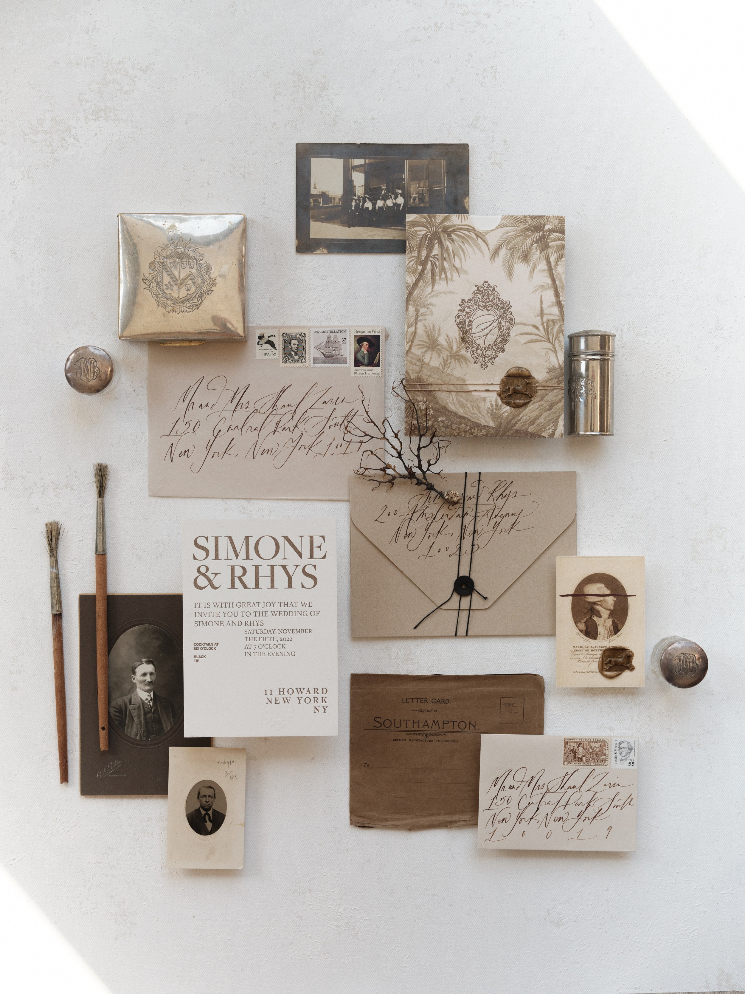 Wedding flat lay photography combining modern typography invitation with vintage heirloom details and calligraphy on a neutral surface