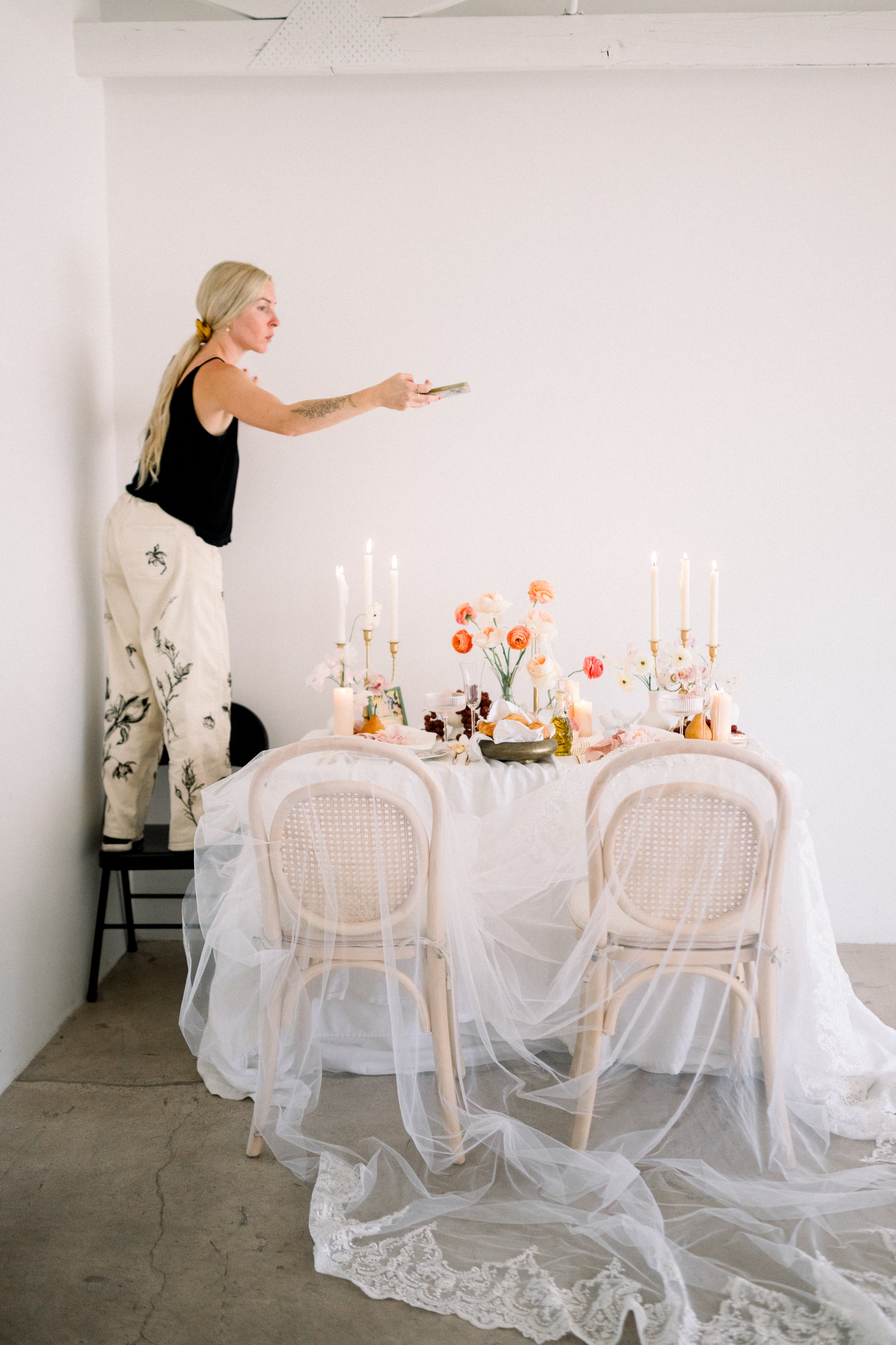behind the scenes of a stylist arranging a styled table setup for a photoshoot in a small studio space.