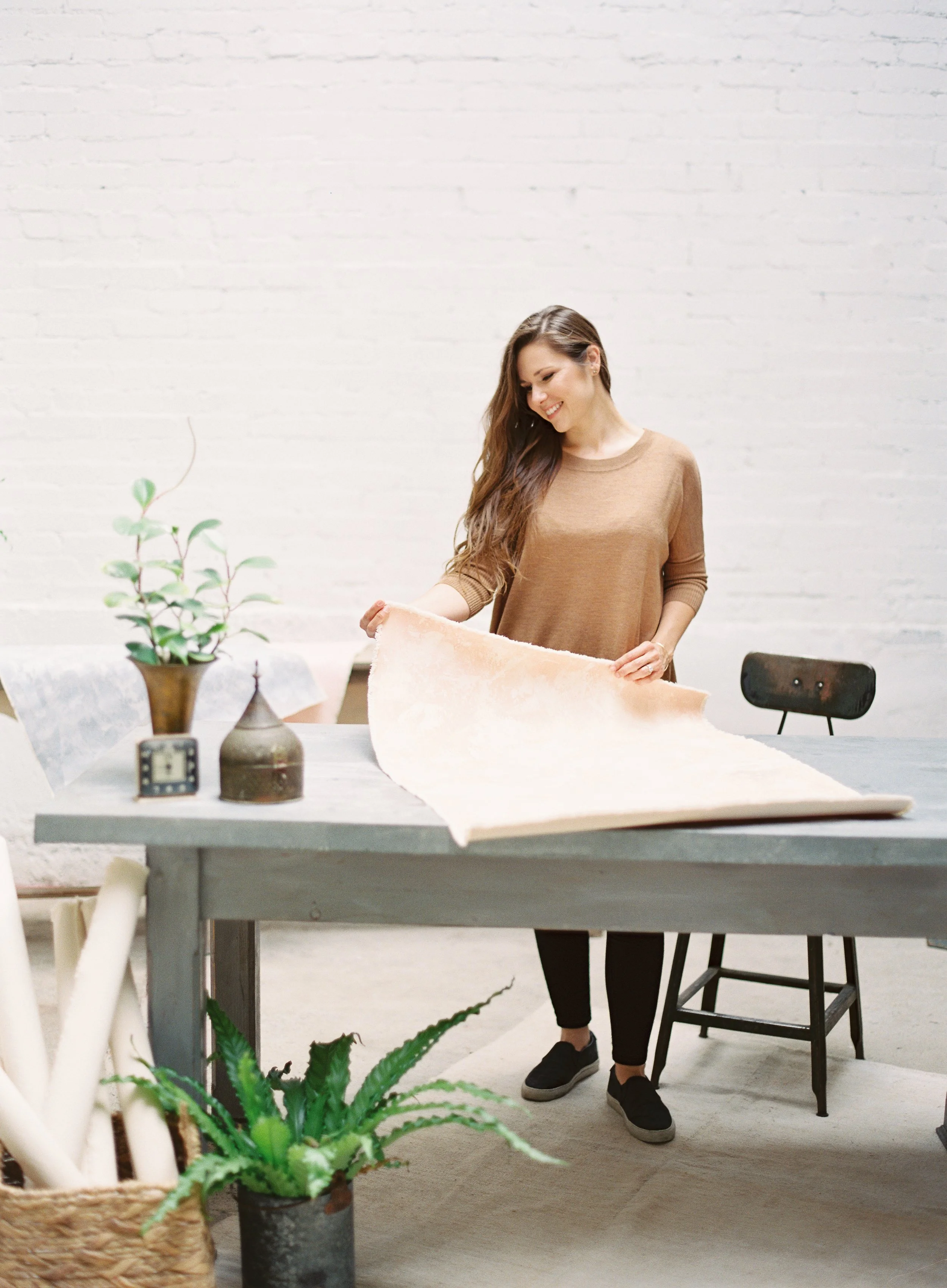 woman laying out a hand-painted canvas backdrop on a table to prepare it for use