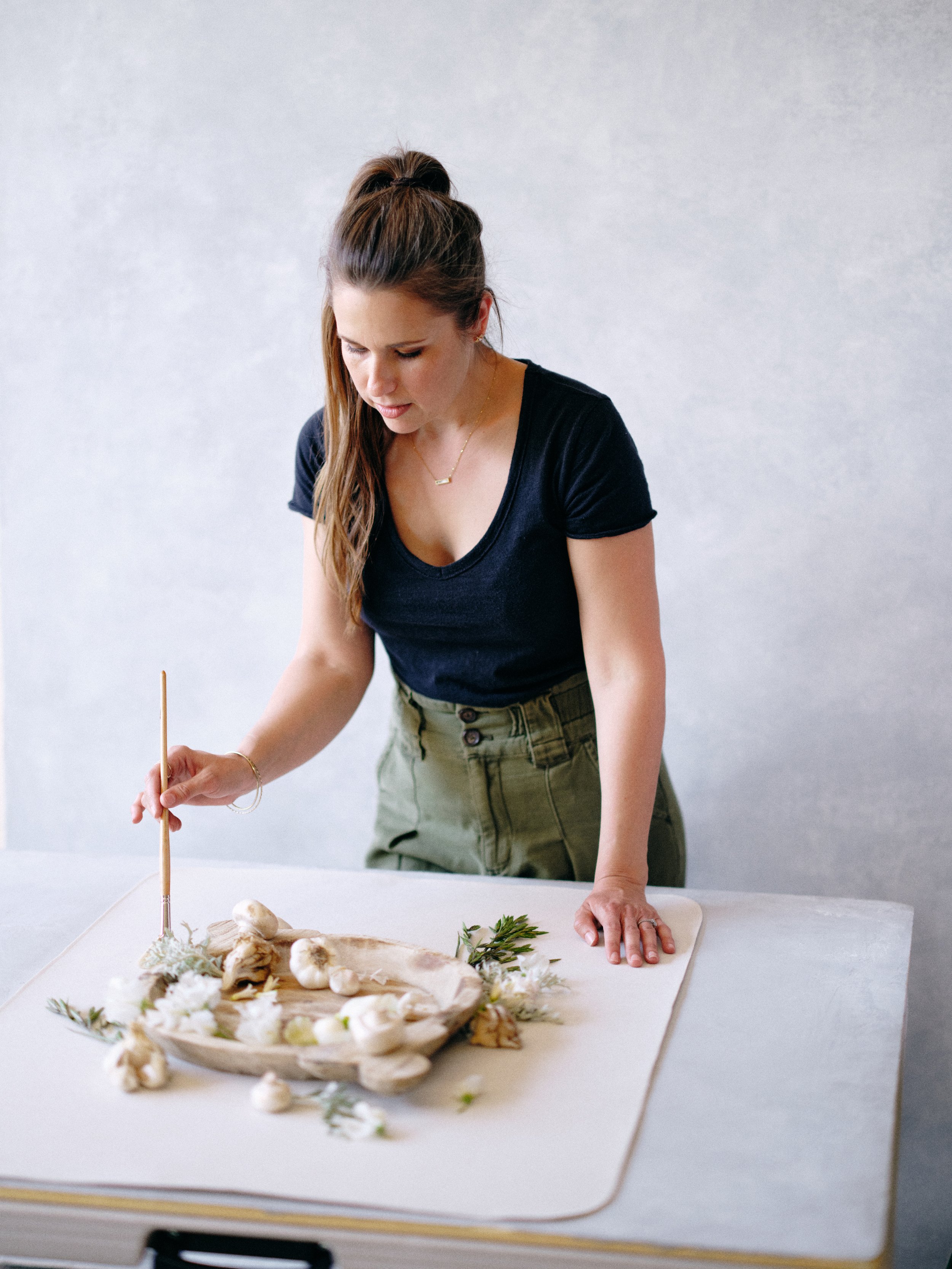 Photographer arranging a flat lay detail shot in front of a cool neutral gray canvas backdrop