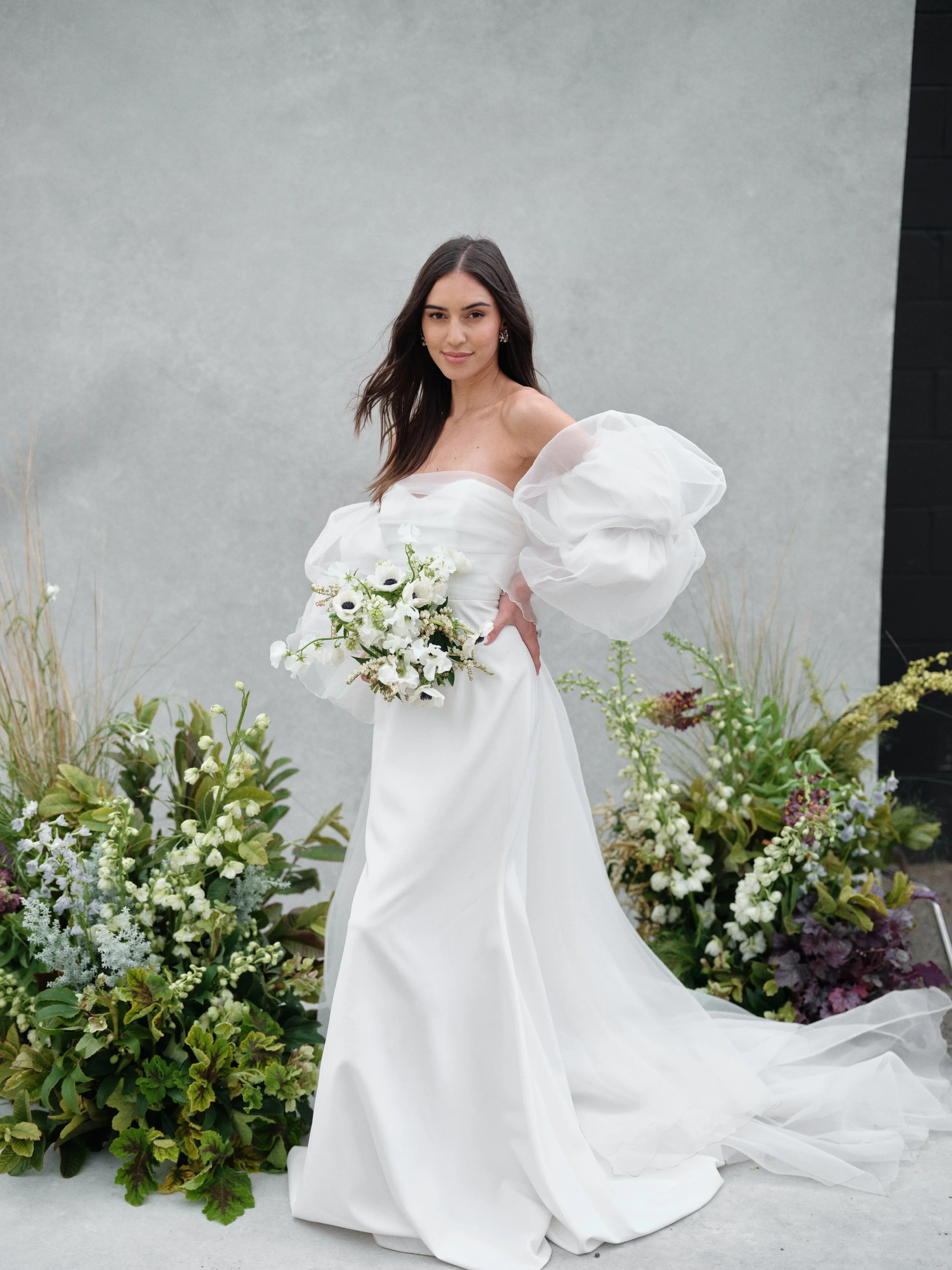Editorial bridal portrait with statement puff sleeves and white bouquet showcasing hotel room getting-ready photography setup