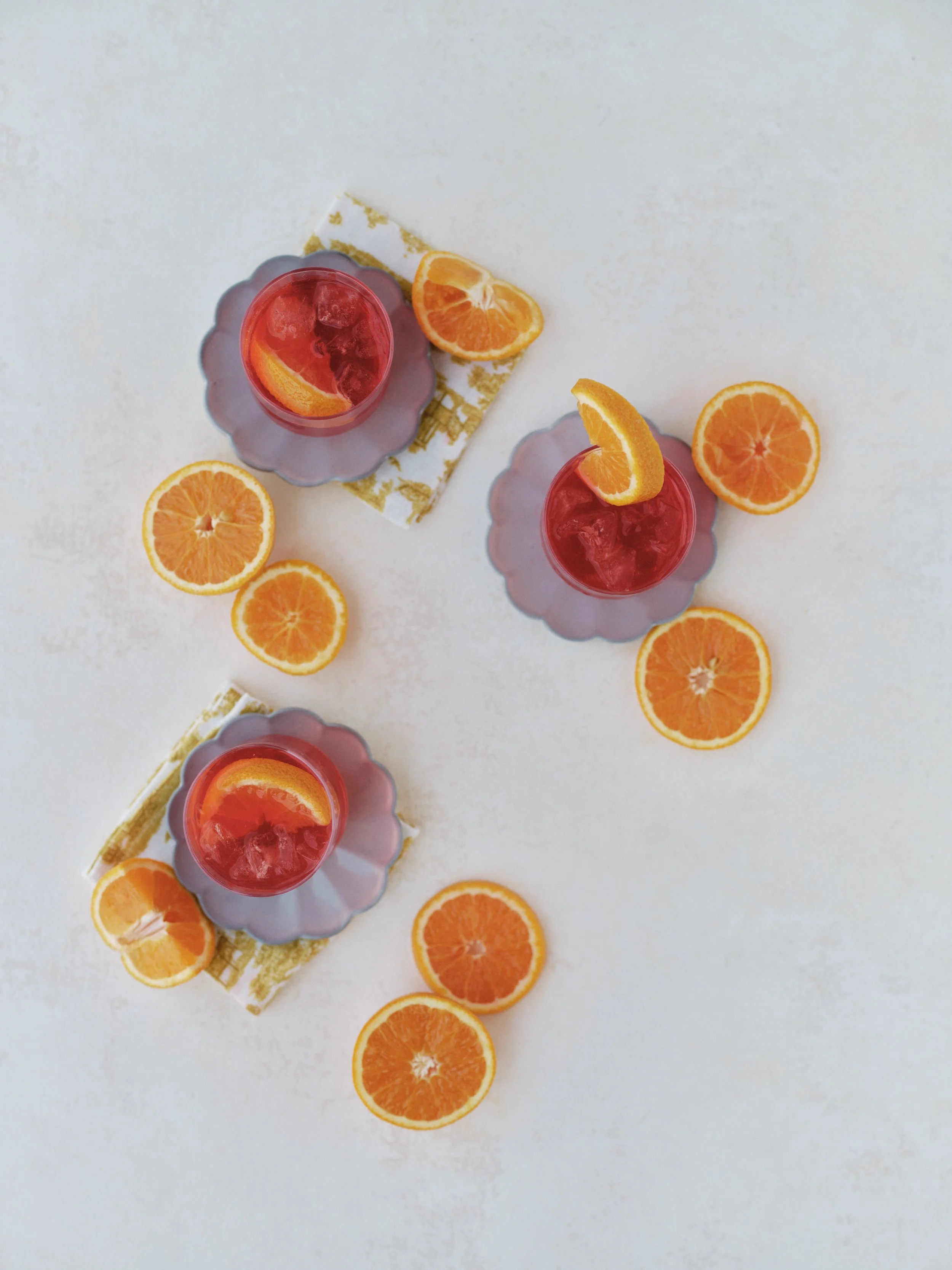 light neutral white photography backdrop styled with complementary color flat lay featuring citrus cocktails in purple glasses demonstrating warm cool contrast for food photography