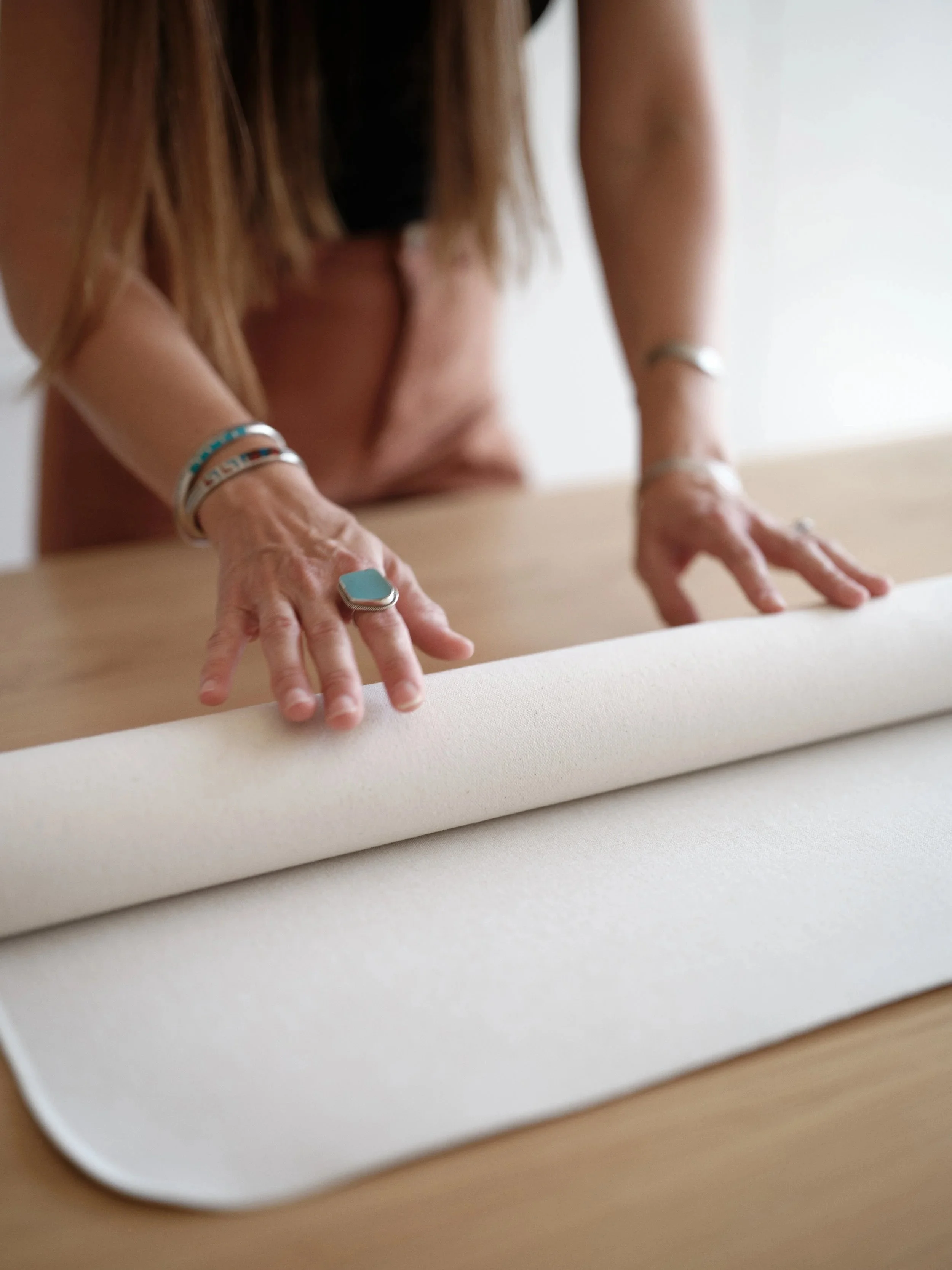 woman rolling a hand-painted canvas backdrop on a wood surface for storage