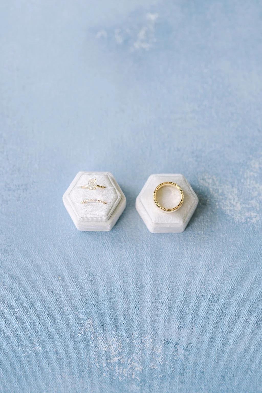 Wedding rings in white velvet hexagon boxes flat lay on a Chasing Stone Celestite hand-painted canvas backdrop