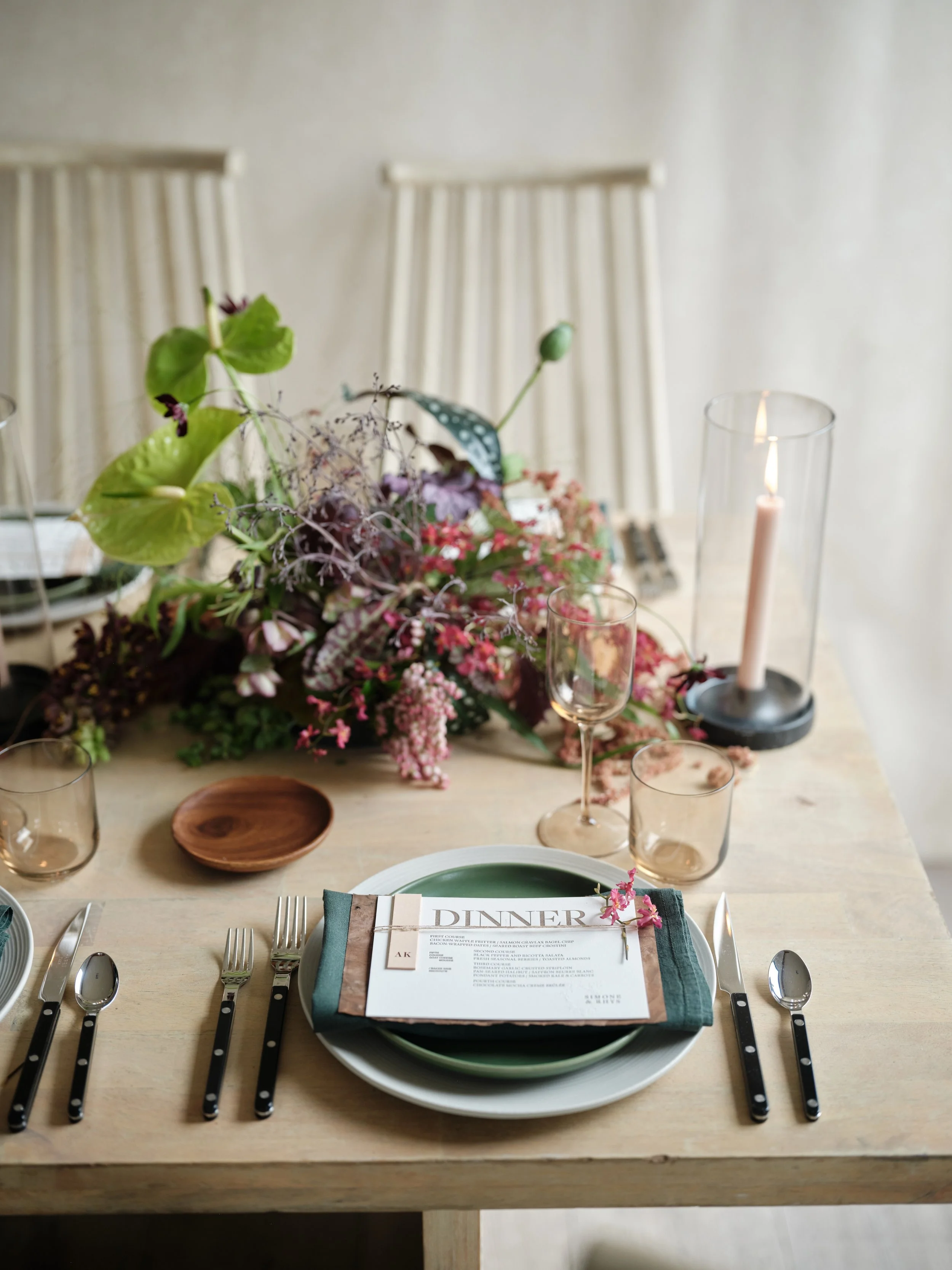 editorial wedding tablescape with sage green place settings, organic floral centerpiece, amber glassware, and a printed dinner menu