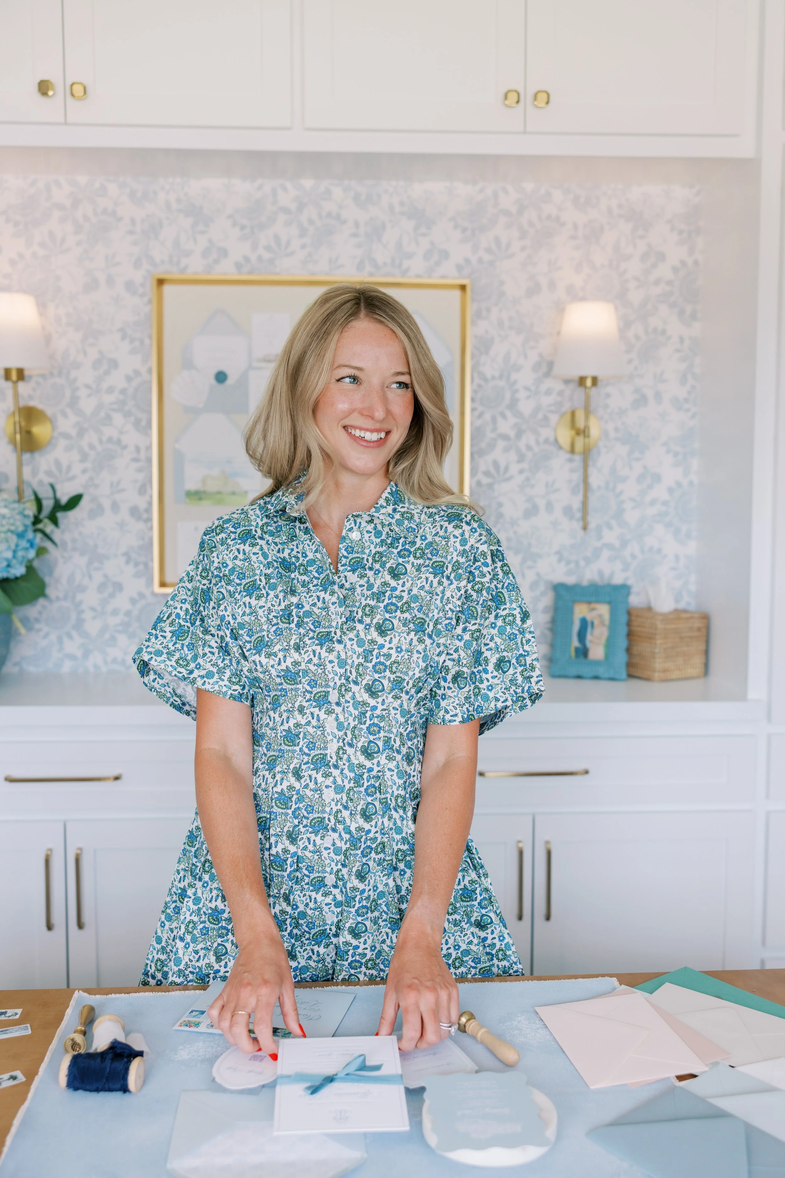 Professional photographer reviewing materials at her studio workspace, planning a corporate headshot backdrop setup with hand-painted canvas backdrops from Chasing Stone