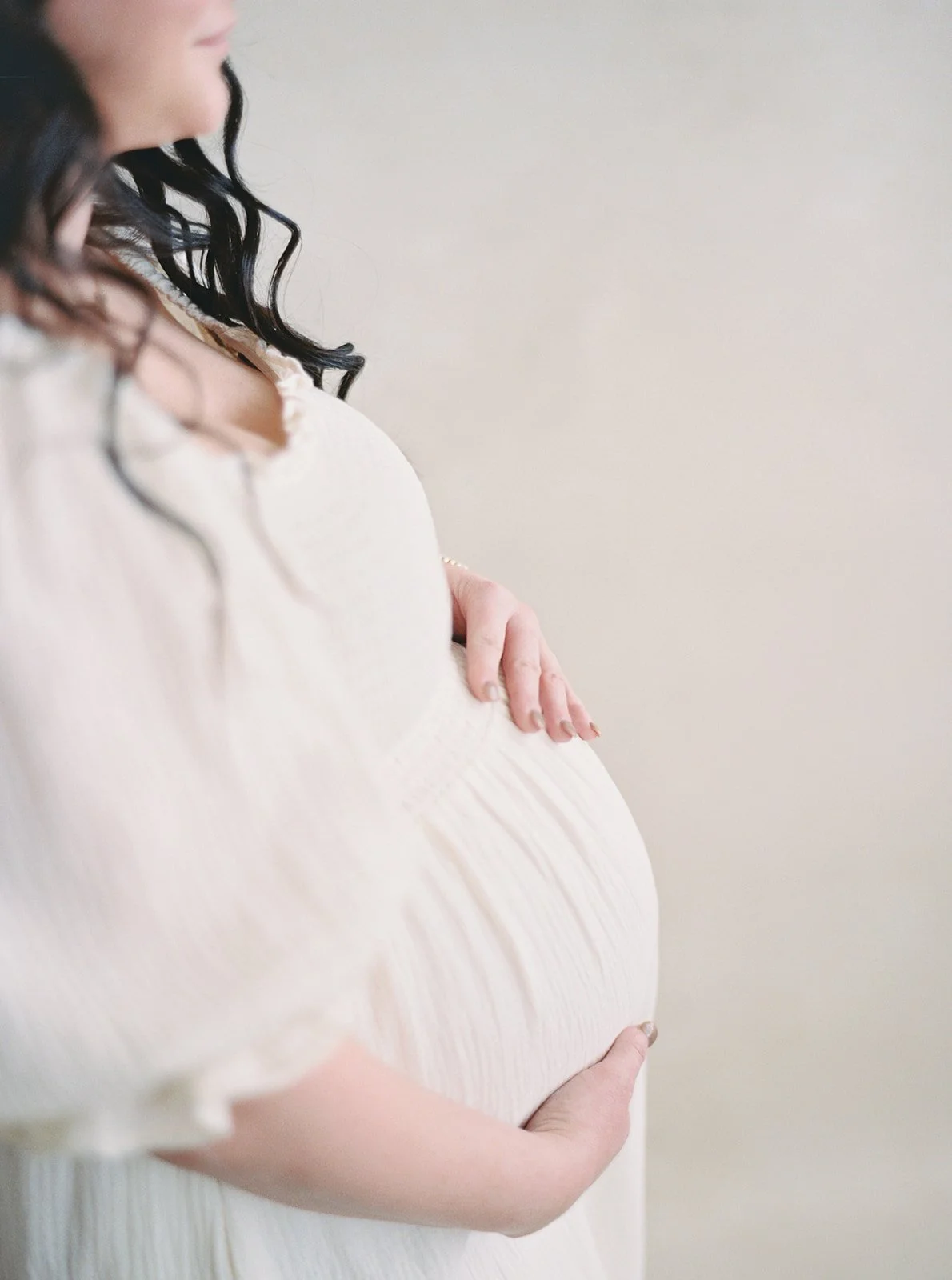 profile silhouette maternity portrait in cream gown against a Chasing Stone Limestone hand-painted canvas backdrop