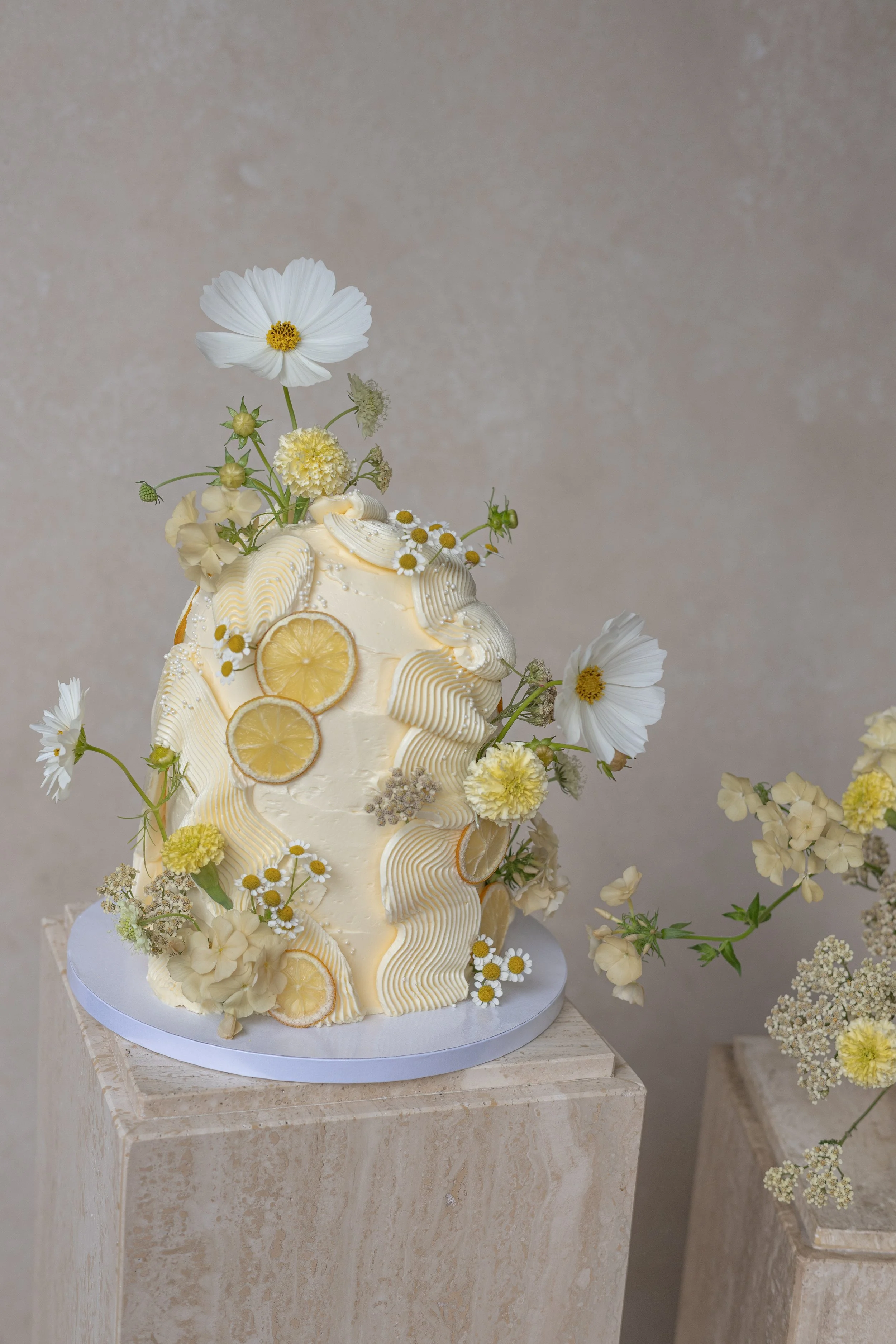 editorial lemon buttercream wedding cake with floral styling against a Chasing Stone Silt hand-painted canvas backdrop