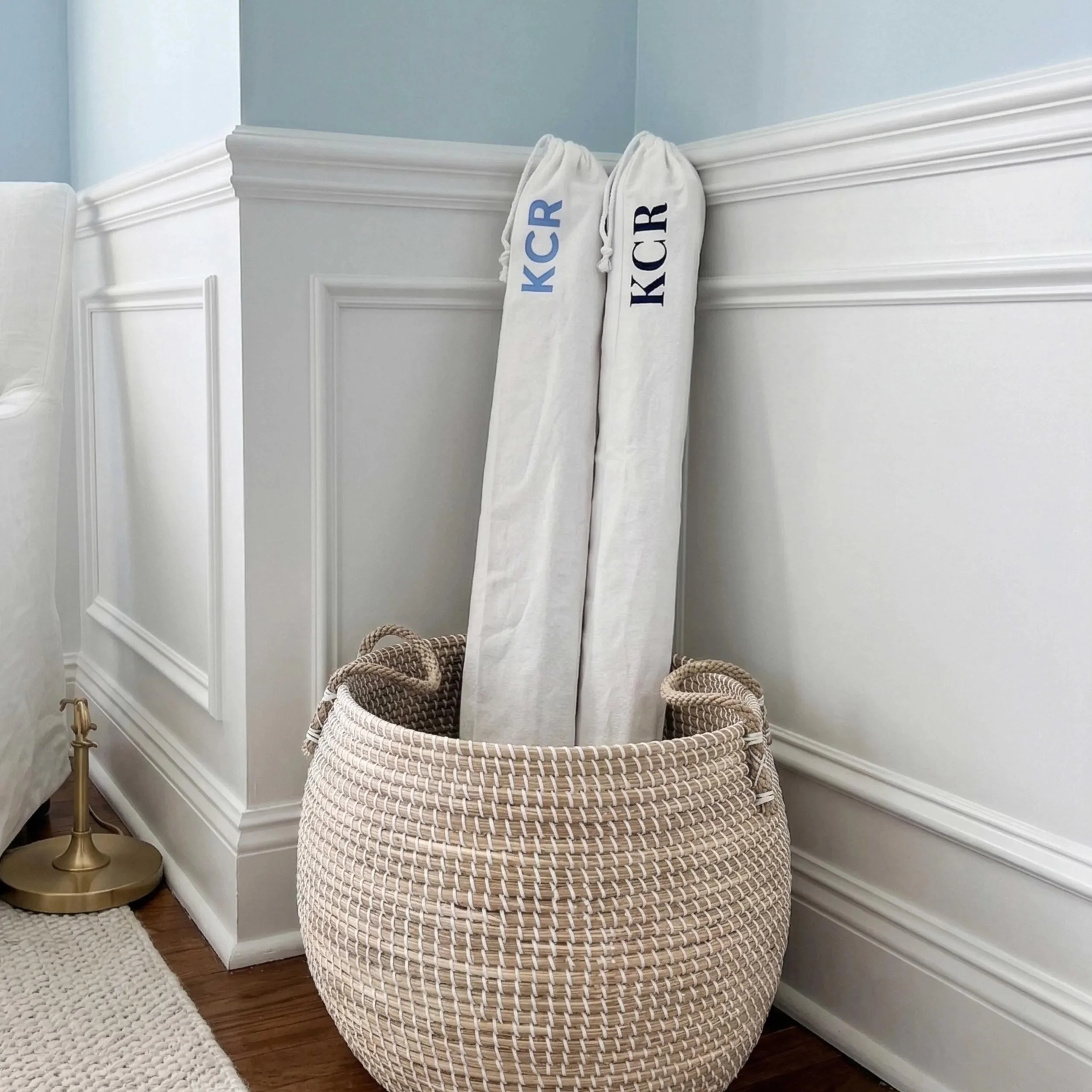 Two rolled canvas backdrops stored vertically in a woven basket in a home studio corner