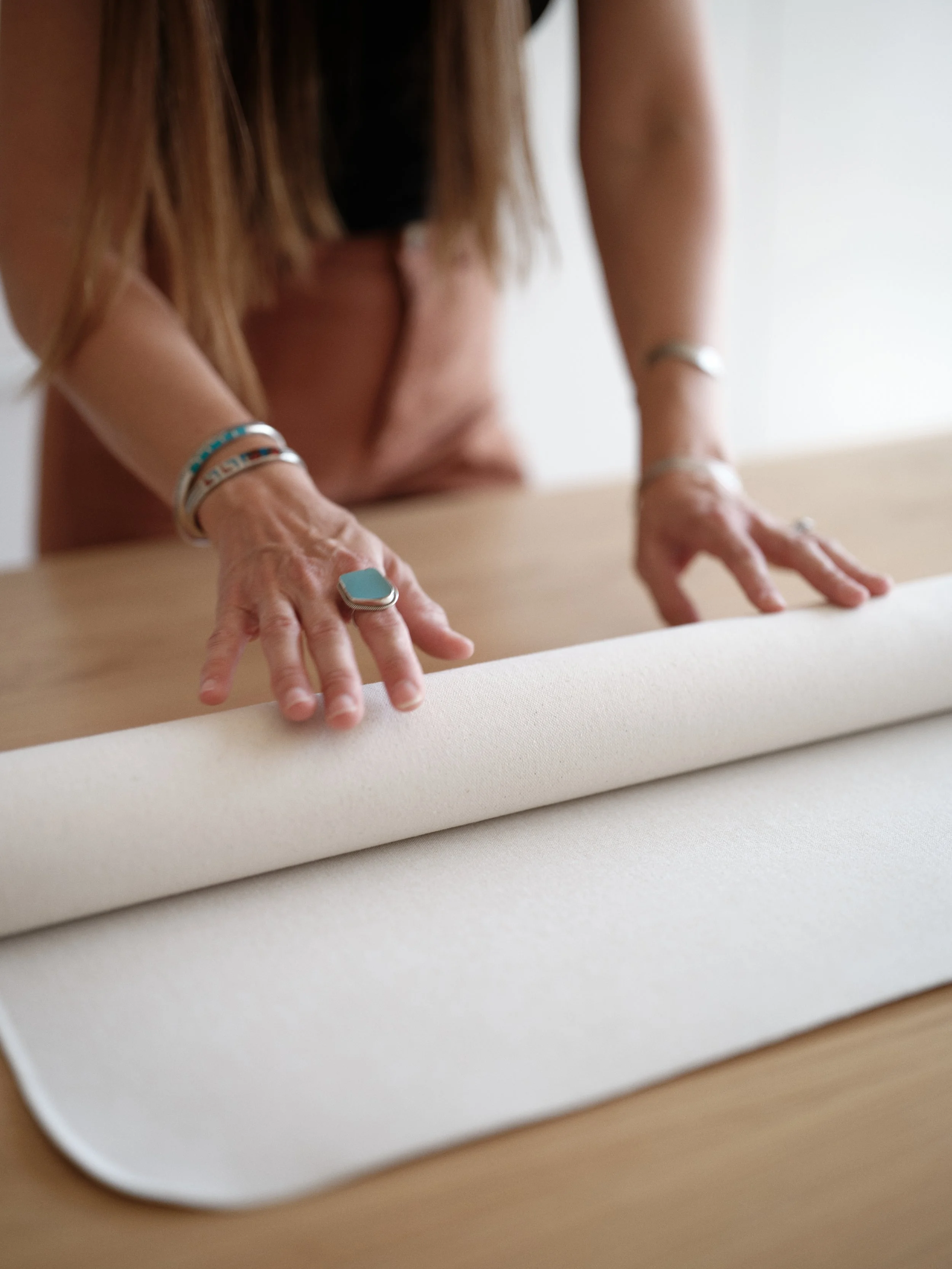 hands rolling hand-painted canvas backdrop for proper storage to prevent wrinkles and creases