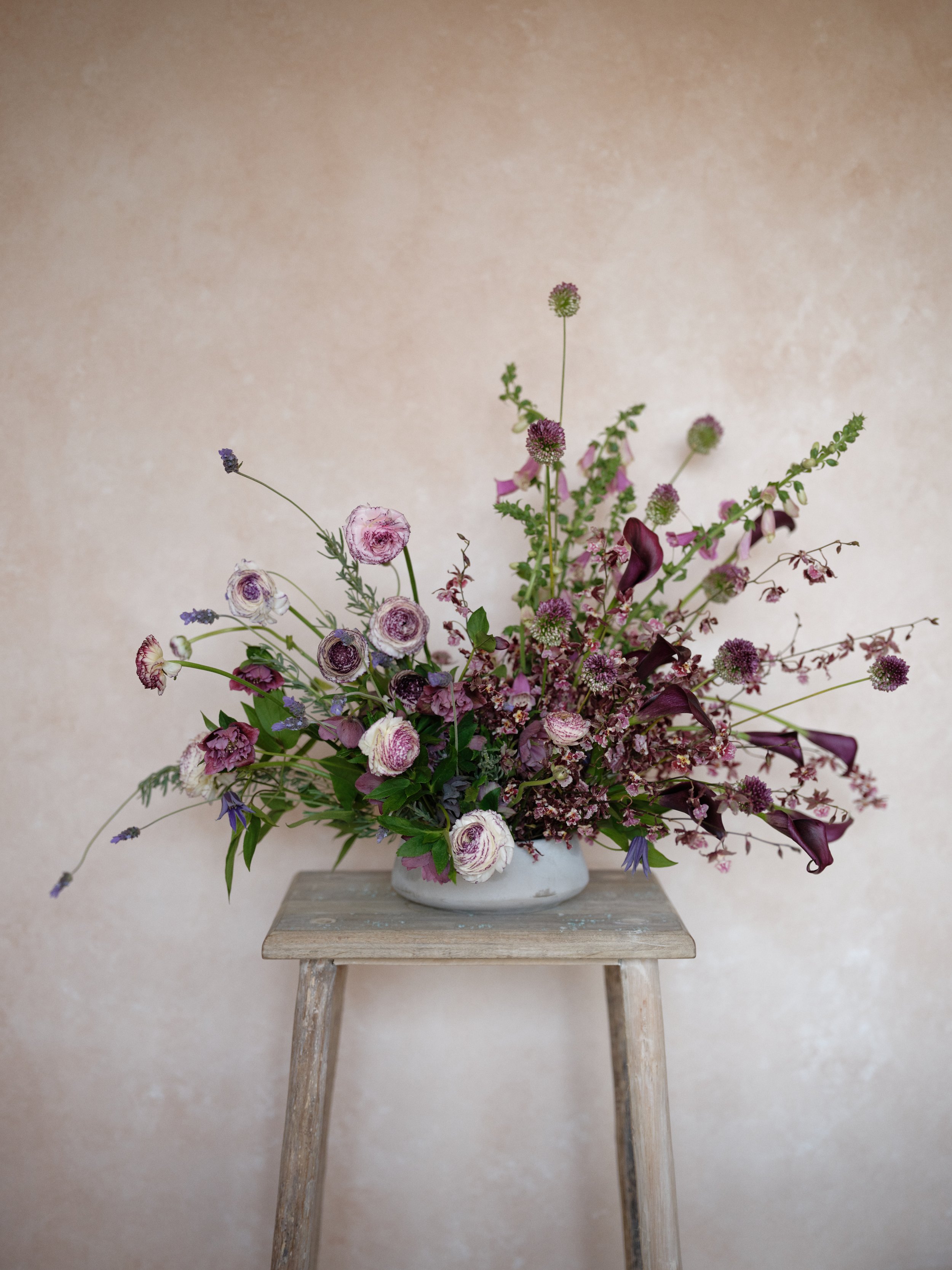 purple and mauve floral arrangement styled on Chasing Stone Clay backdrop for product photography