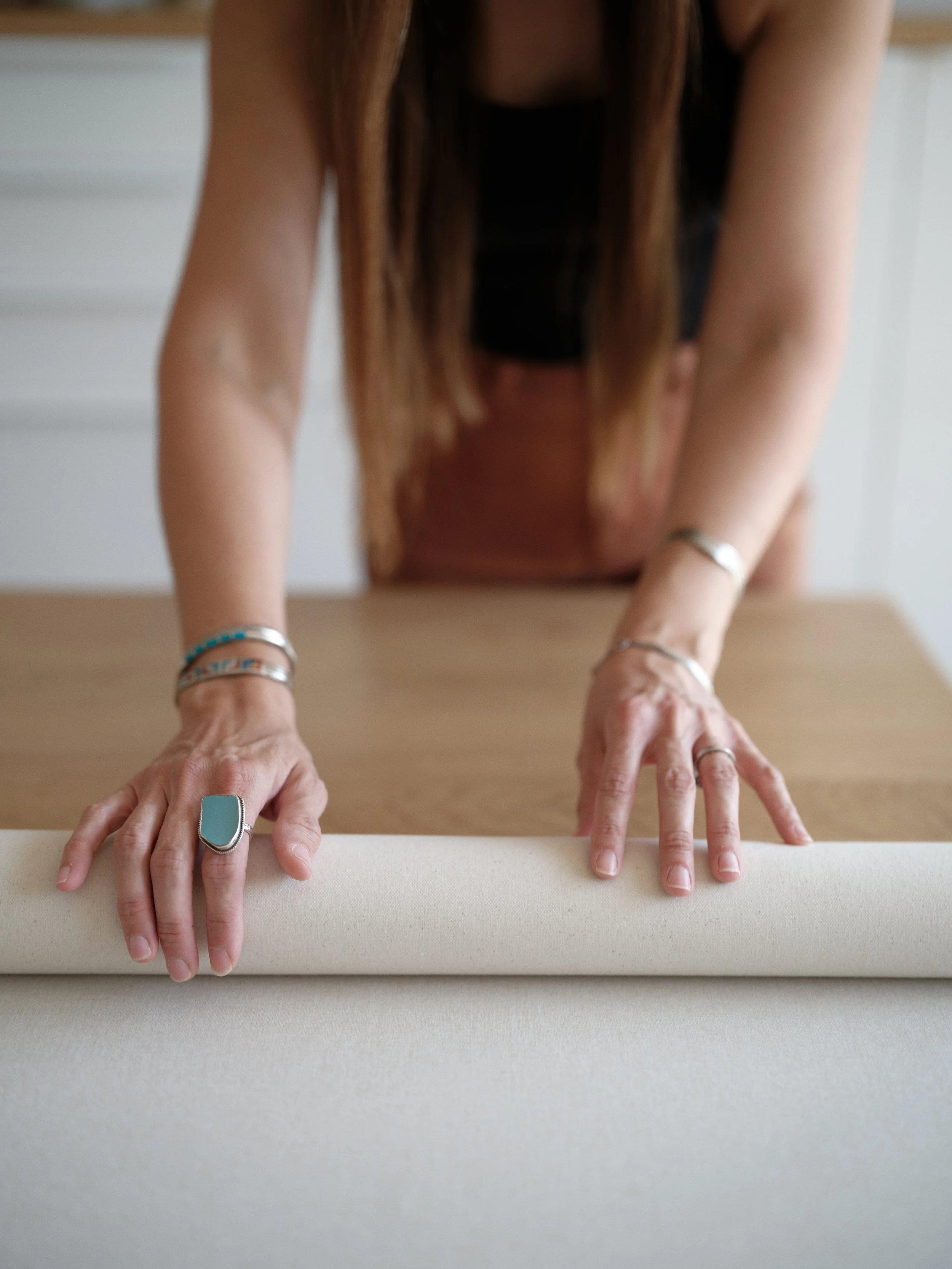 hands rolling a hand-painted canvas backdrop for proper storage and care