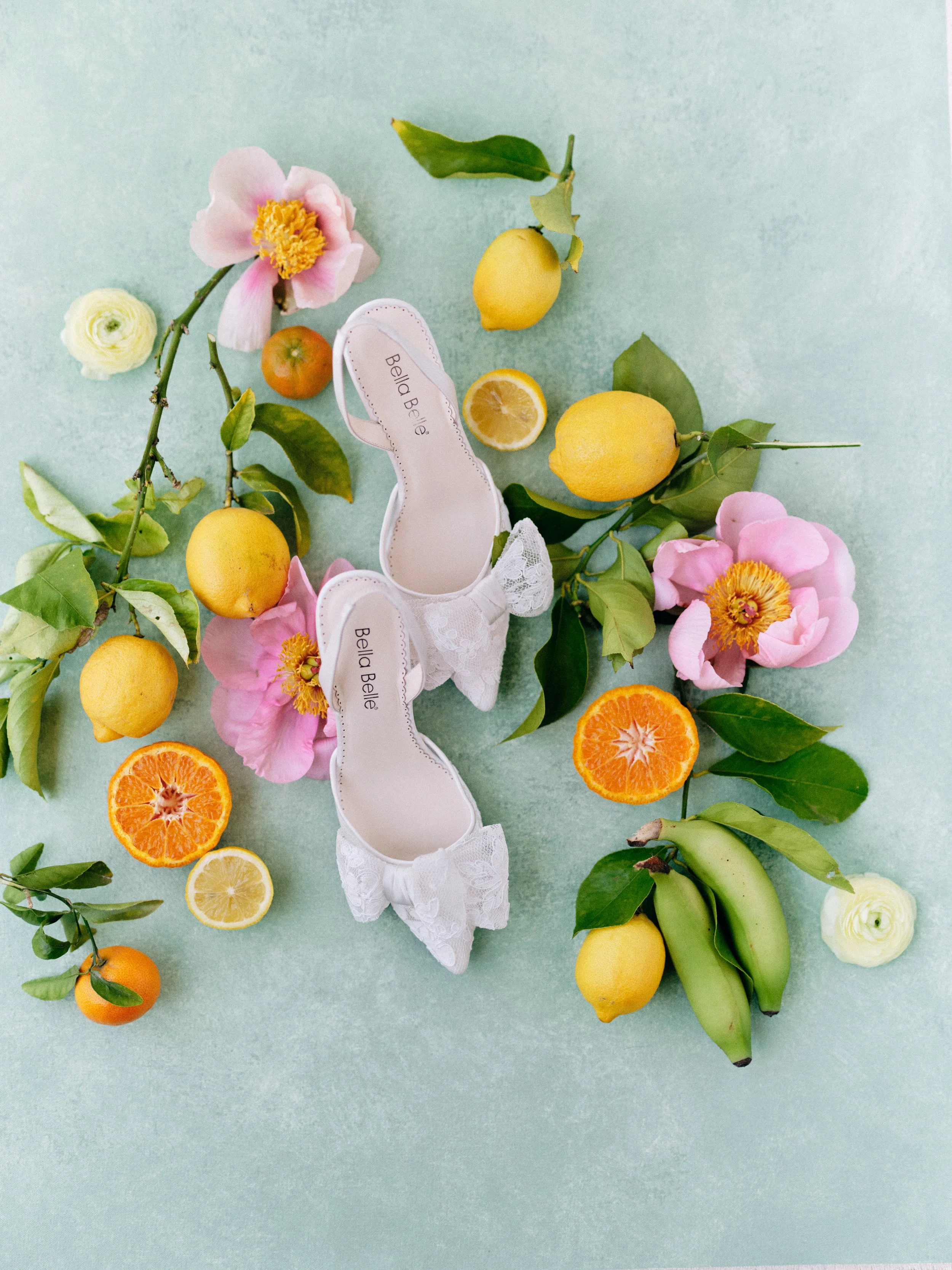 bridal flat lay styling with citrus, flowers, and wedding shoes on Chasing Stone Celadonite backdrop for product photography