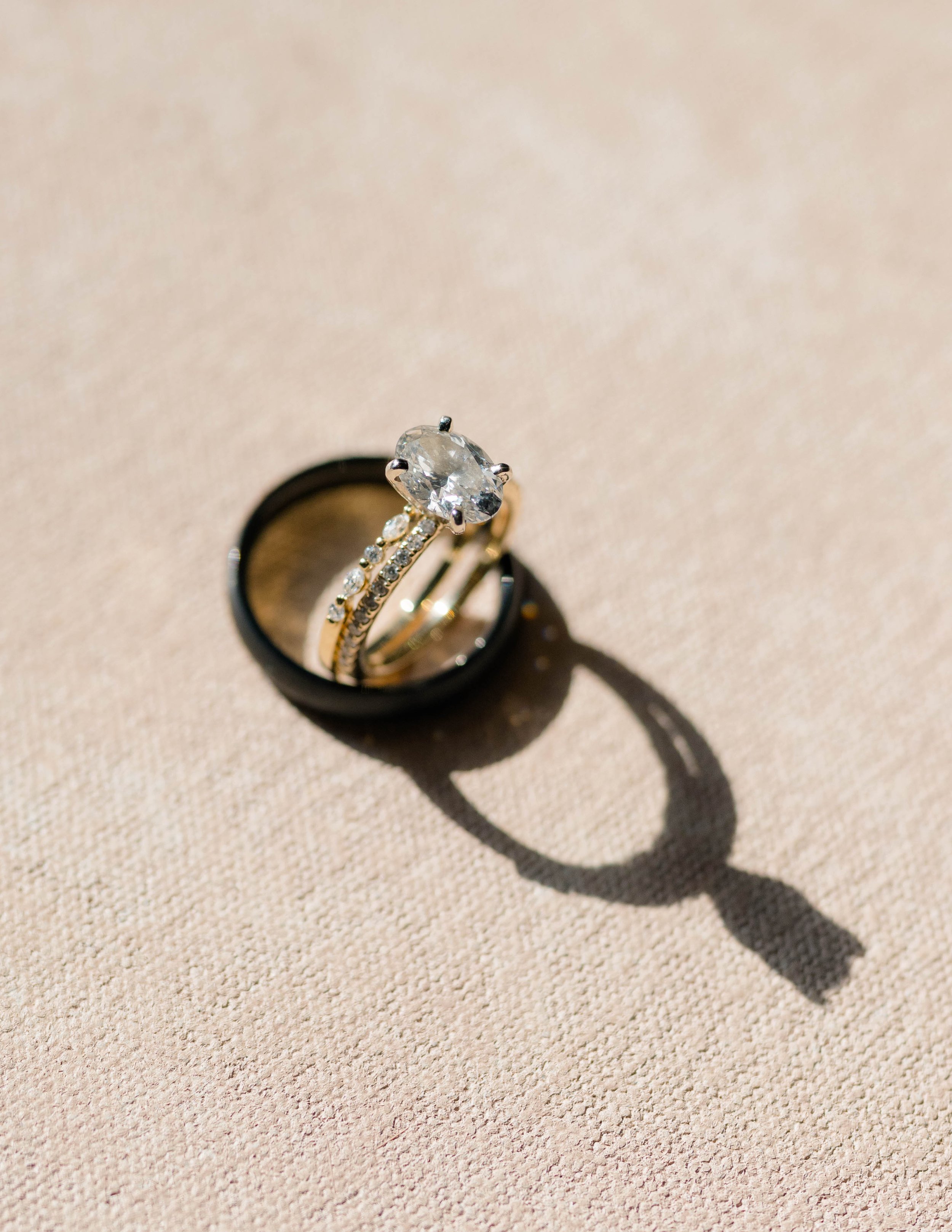 Oval diamond engagement ring and wedding band on a Chasing Stone flat lay fabric surface