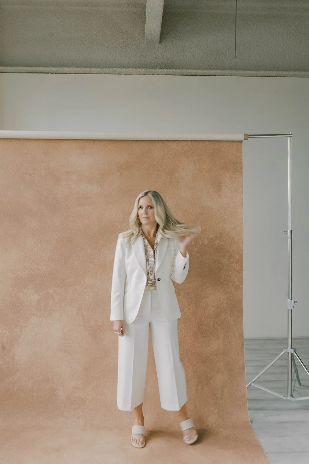 Portrait of woman standing in front of a hand-painted photography backdrop on a studio stand