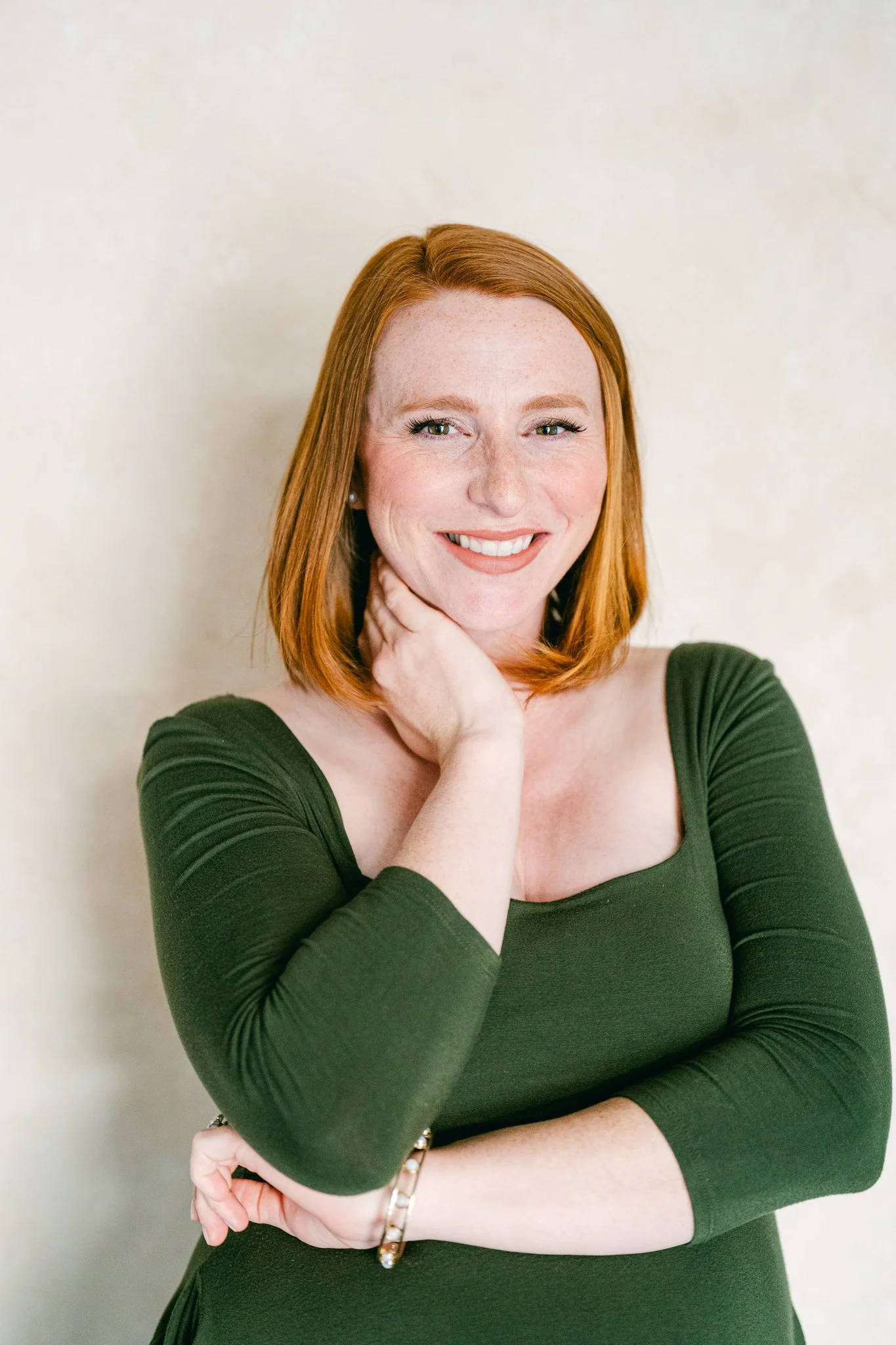 Professional headshot portrait of a smiling woman photographed on a neutral hand-painted backdrop used for mini session photography