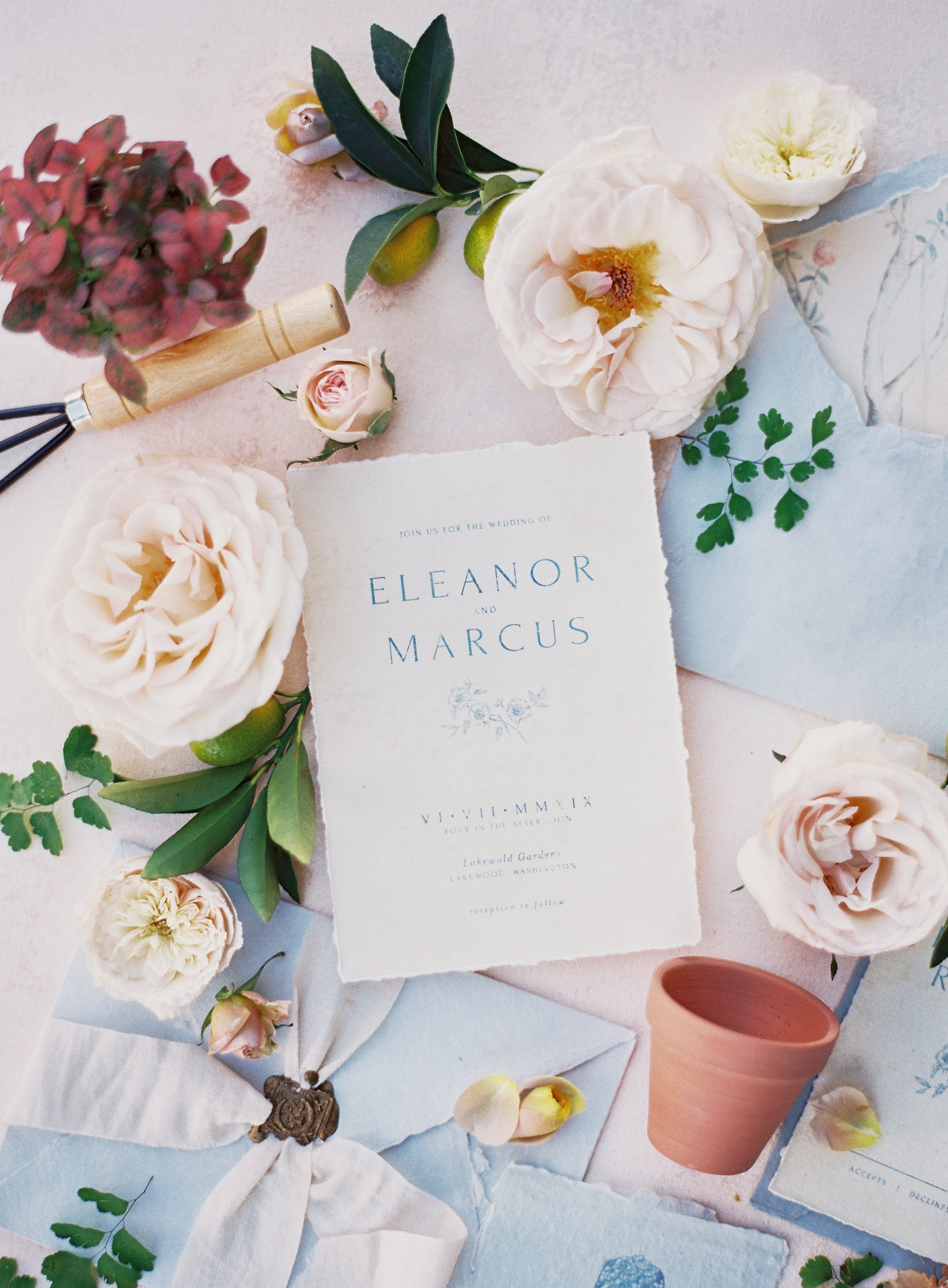floral wedding invitation flat lay on textured canvas backdrop with envelopes and soft natural light