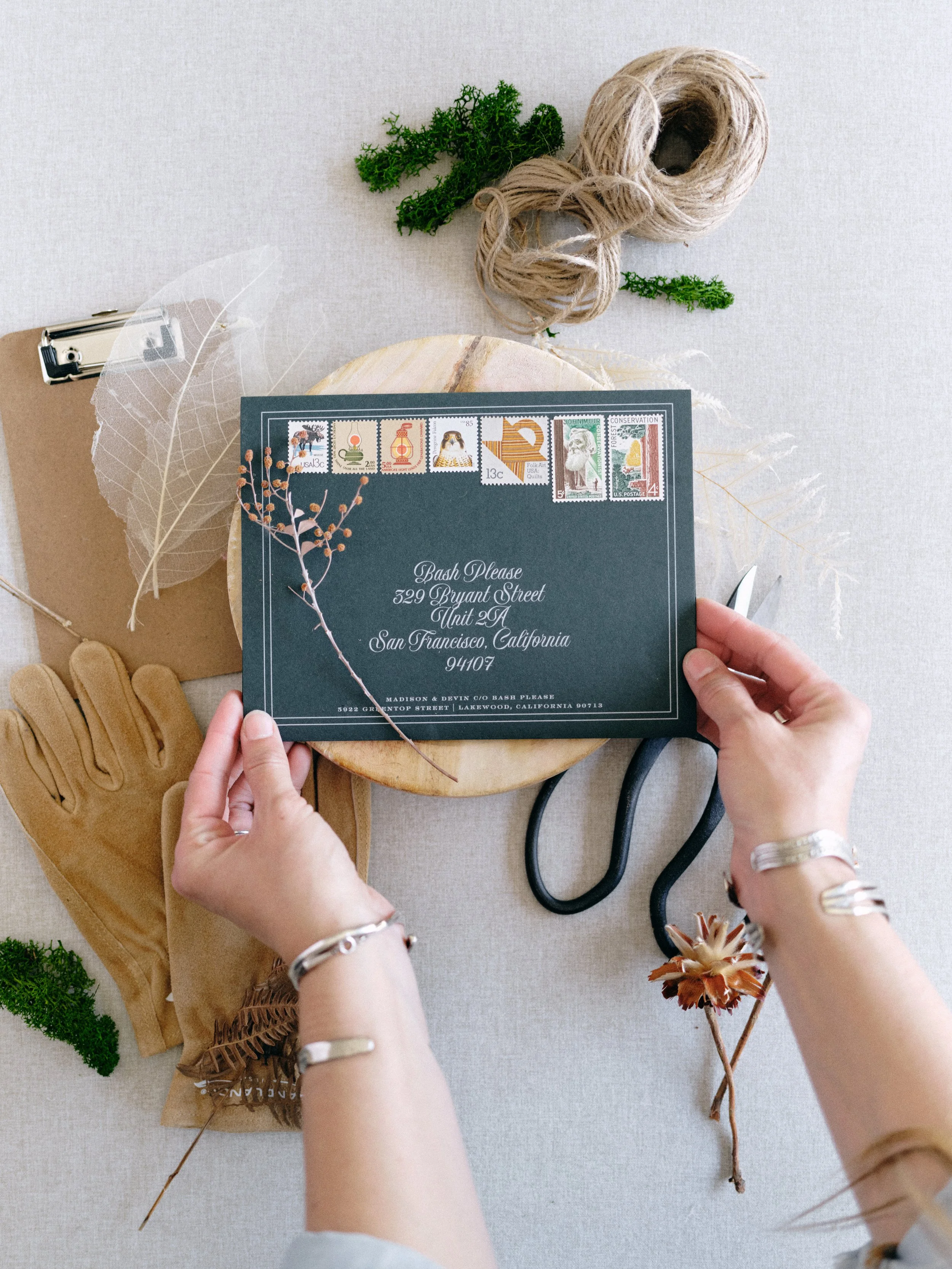 Wedding invitation flat lay demonstrating a clear hero element surrounded by natural styling props on a Chasing Stone linen surface
