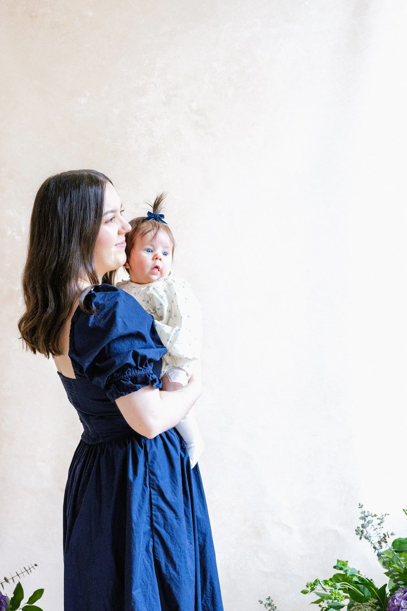 mother holding her baby in front of a Chasing Stone Limestone hand-painted canvas backdrop