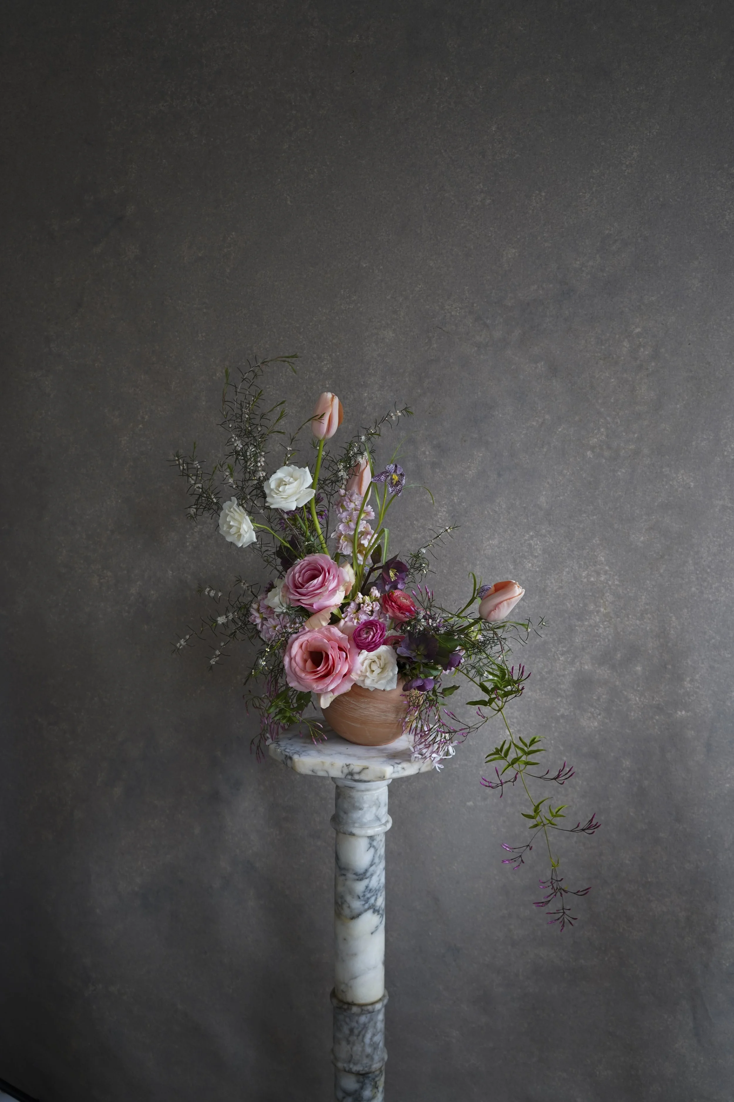 Editorial floral arrangement on a marble pedestal against a Chasing Stone Graphite hand-painted canvas backdrop