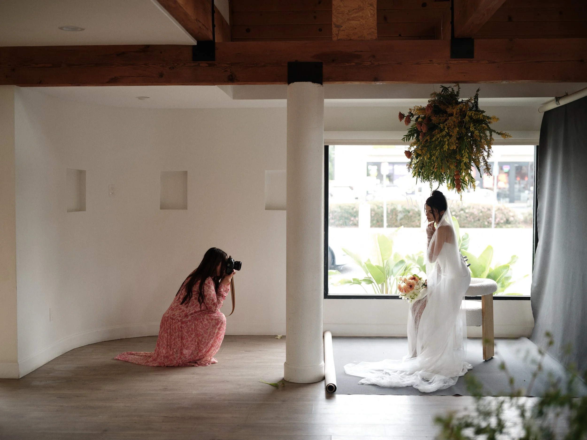 photographer capturing bride portrait with canvas backdrop and natural window light