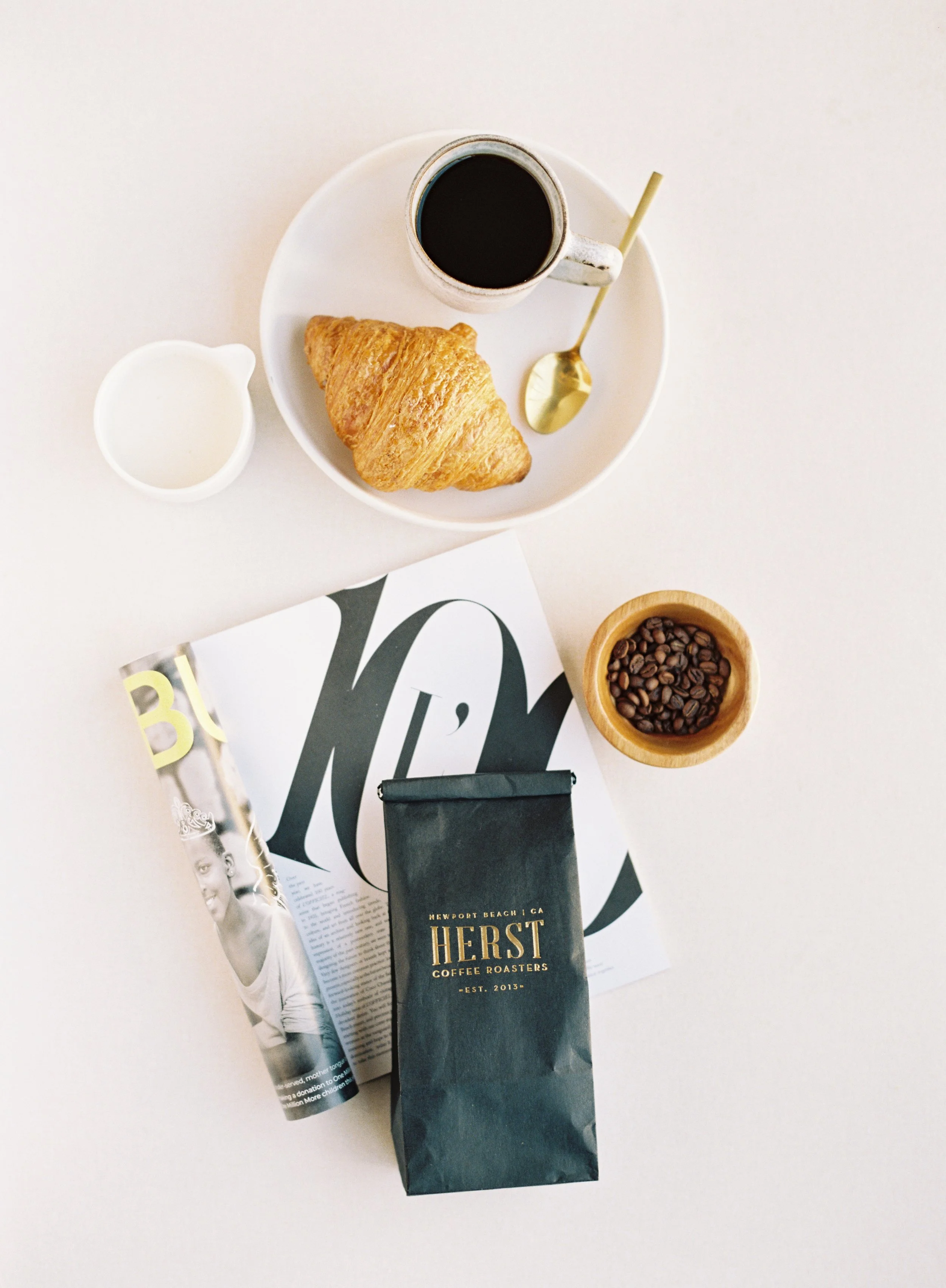 Flat lay photography demonstrating triangular composition with coffee, magazine, and coffee bag arranged in three-point pattern on white YARROW styling surface