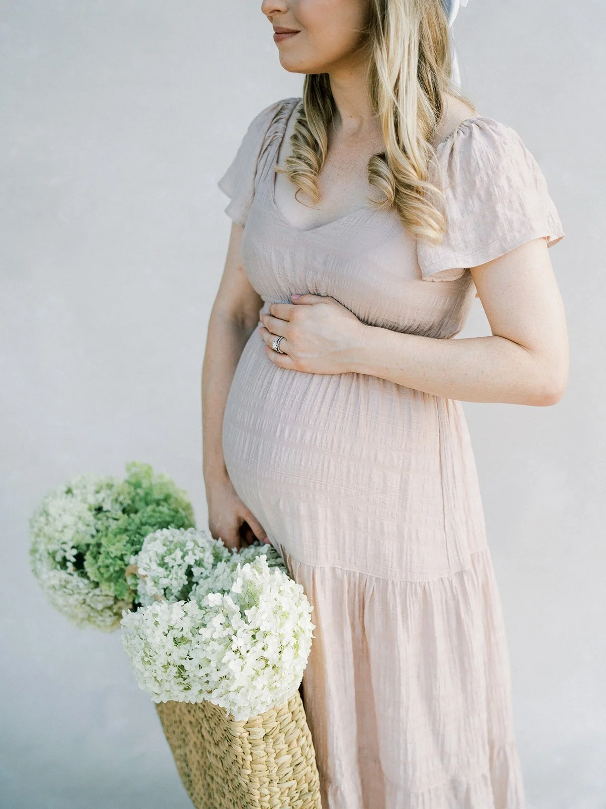 maternity portrait on a Chasing Stone Silt hand-painted canvas backdrop with expecting mother in blush linen dress holding hydrangeas