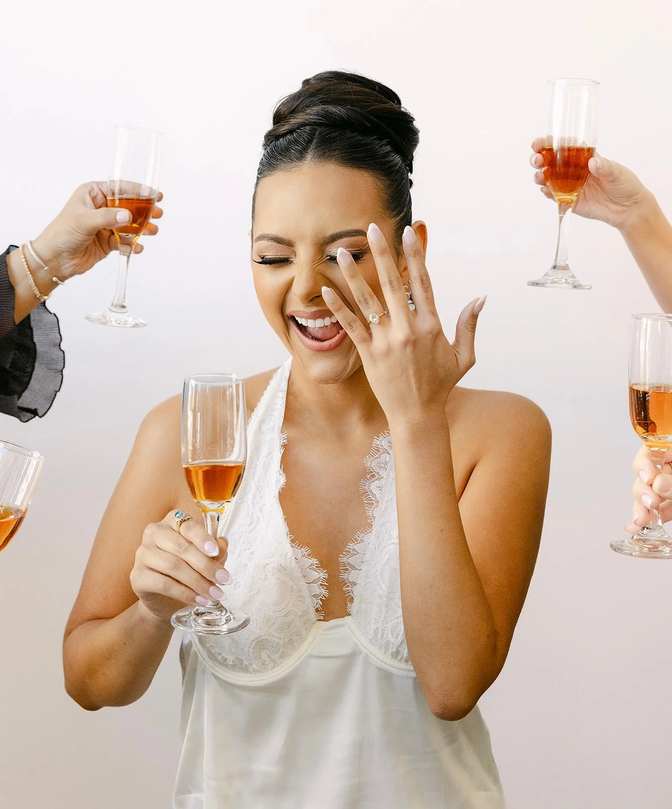 Bride laughing with bridesmaids during champagne toast on hand-painted canvas backdrop