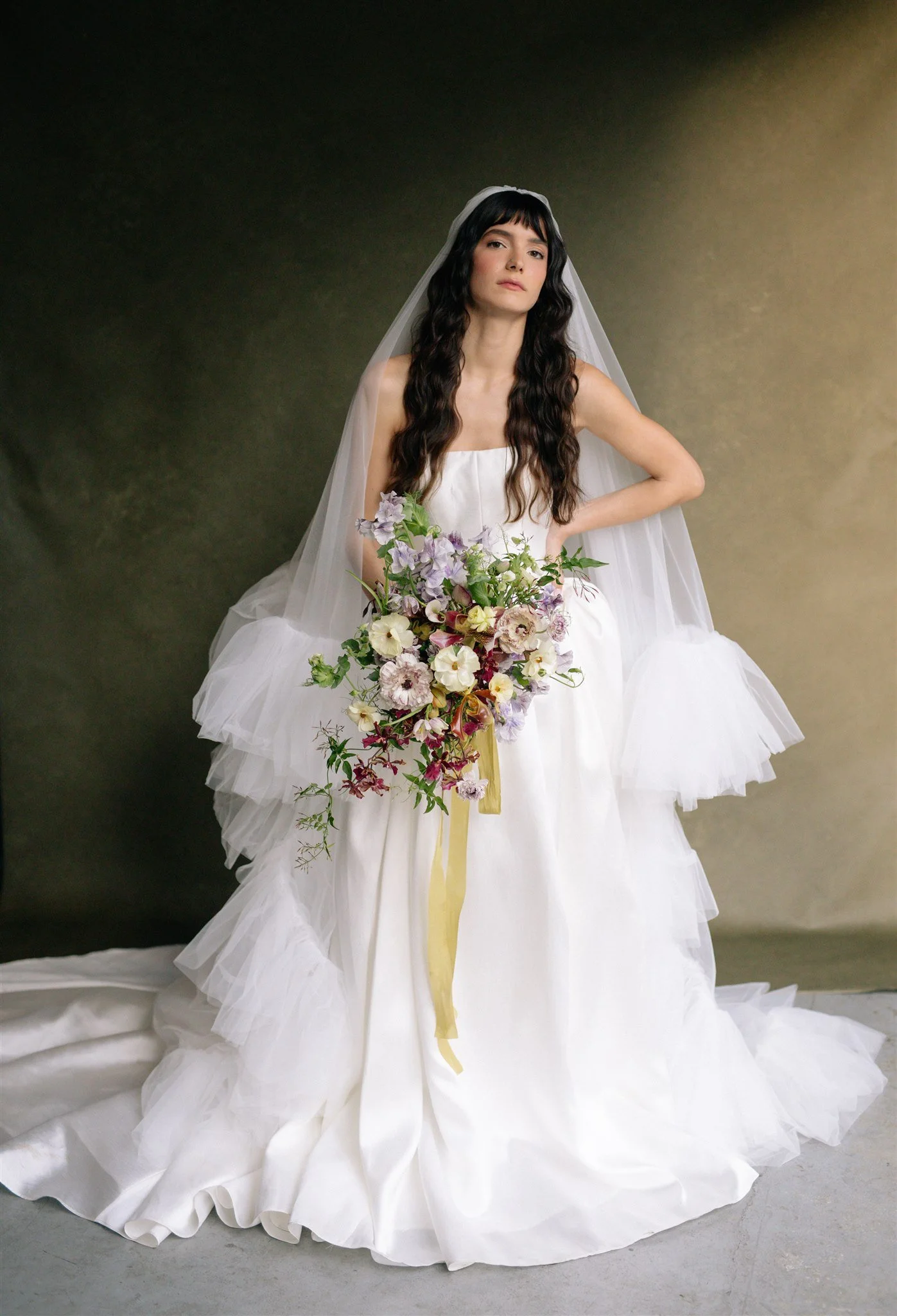 editorial bridal portrait of a bride with cathedral veil and wild garden bouquet against a deep green hand-painted canvas backdrop