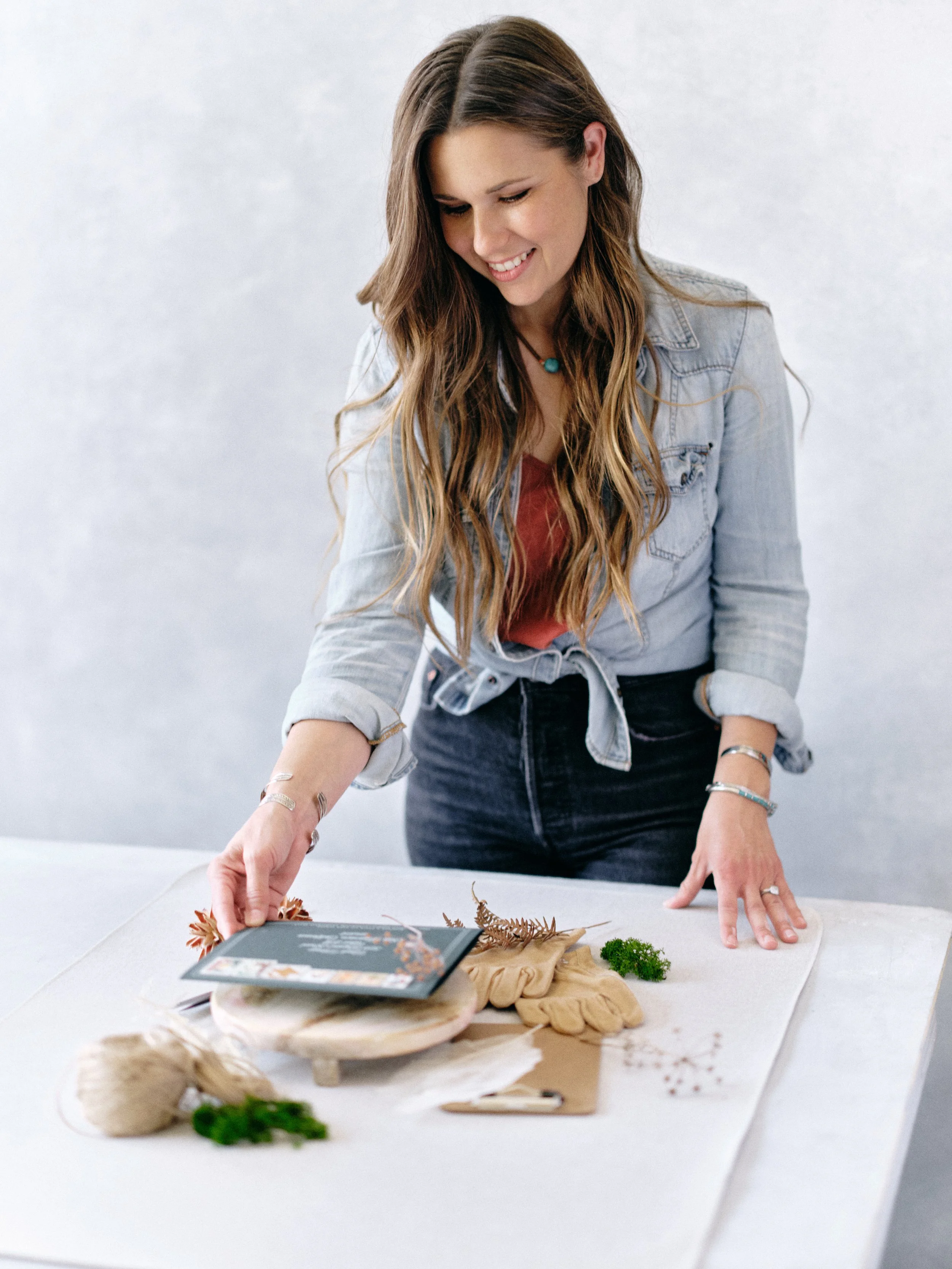 Chasing Stone founder Jennifer styling a flat-lay scene on a hand-painted canvas surface